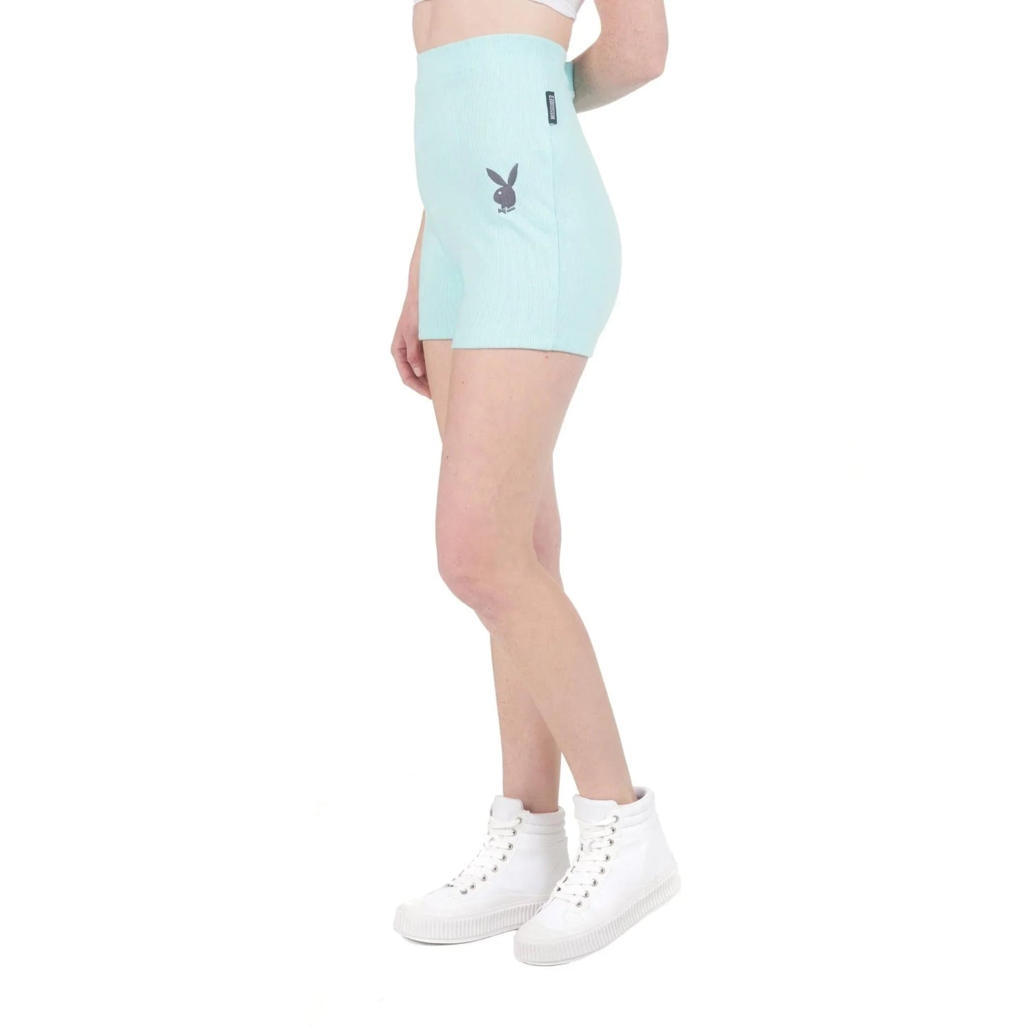 Woman wearing light blue high-waisted biking shorts with logo and white high-top sneakers