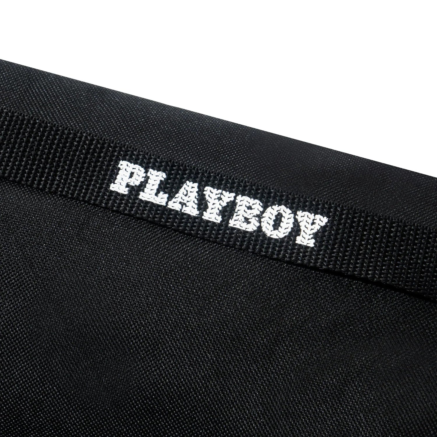 Black fanny pack with white PLAYBOY logo on textured strap, close-up view.