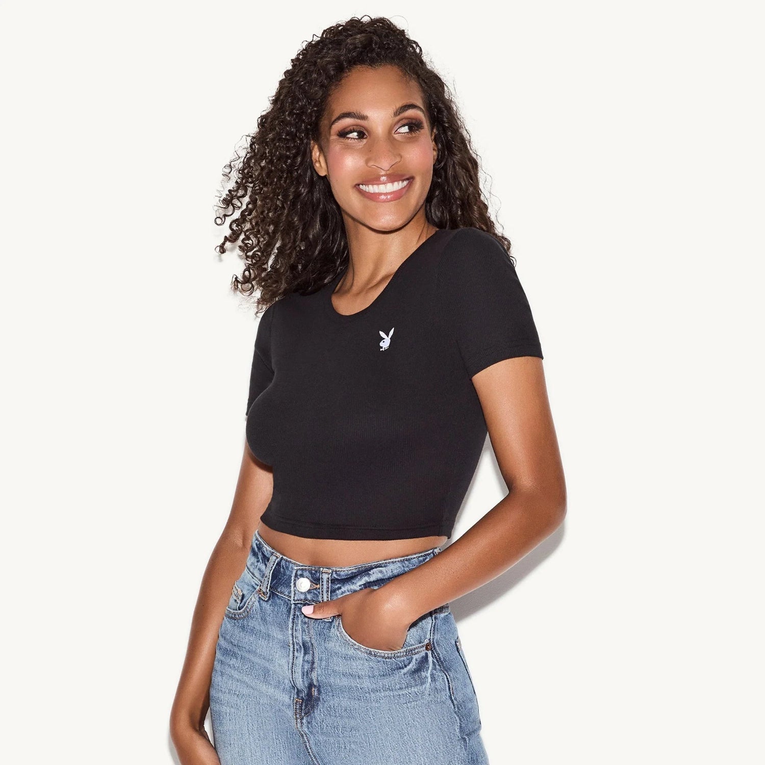 Woman wearing black baby tee with white rabbit logo and high-waisted blue jeans