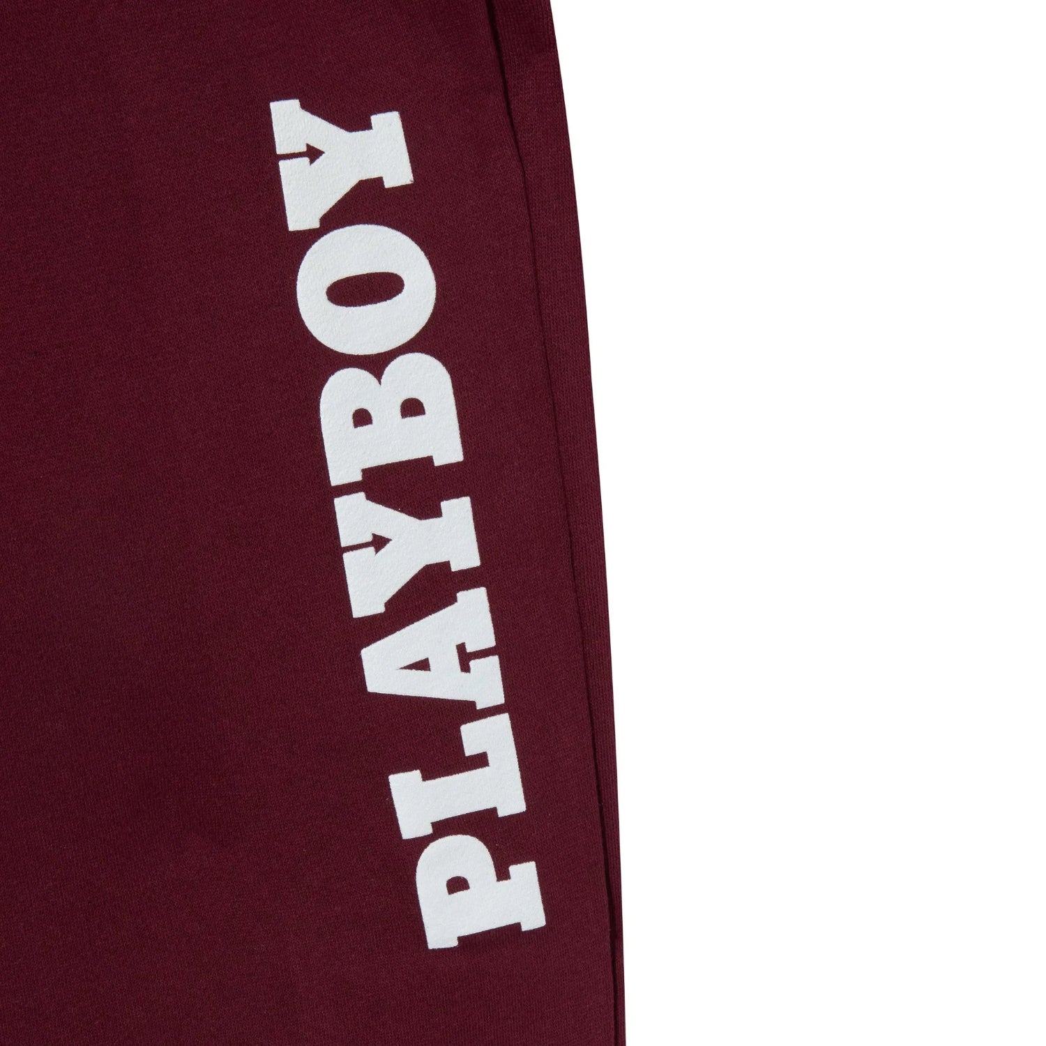 Maroon sweatpants with bold white PLAYBOY text on the leg, lifestyle apparel closeup