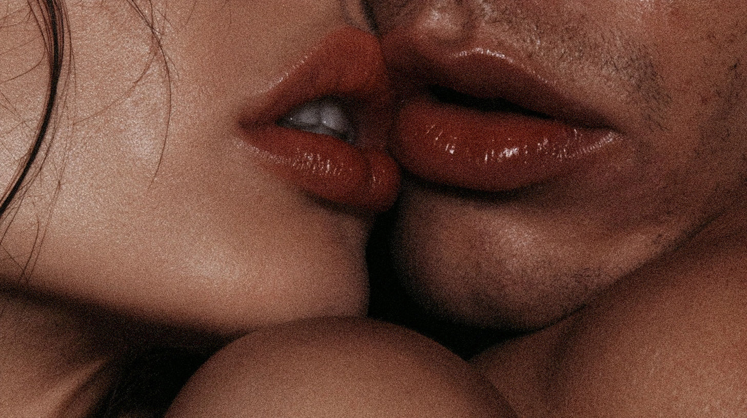 A close, warm-toned crop of two people about to kiss, shot on grainy film.