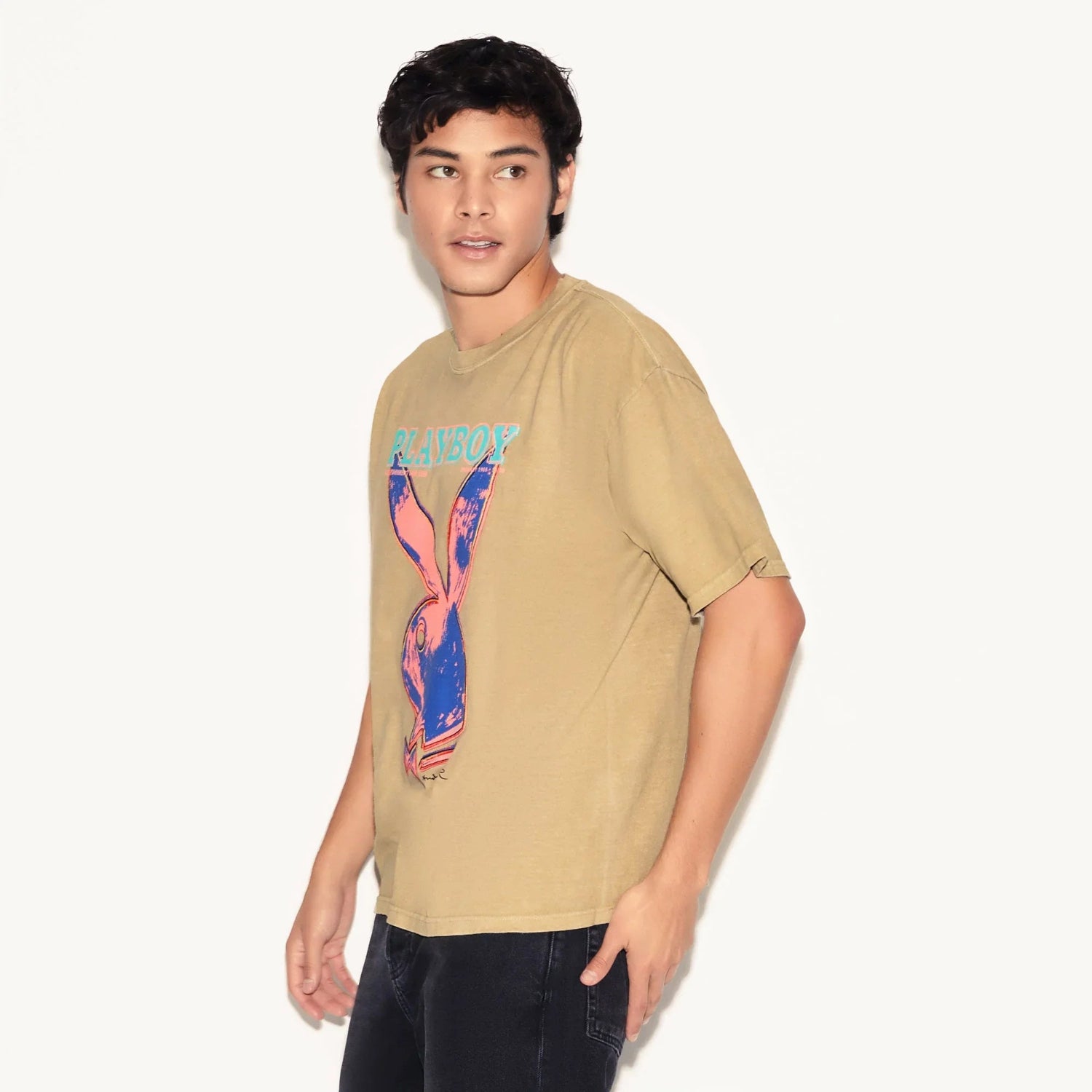 Man wearing tan t-shirt with colorful pop art bunny graphic and text on front
