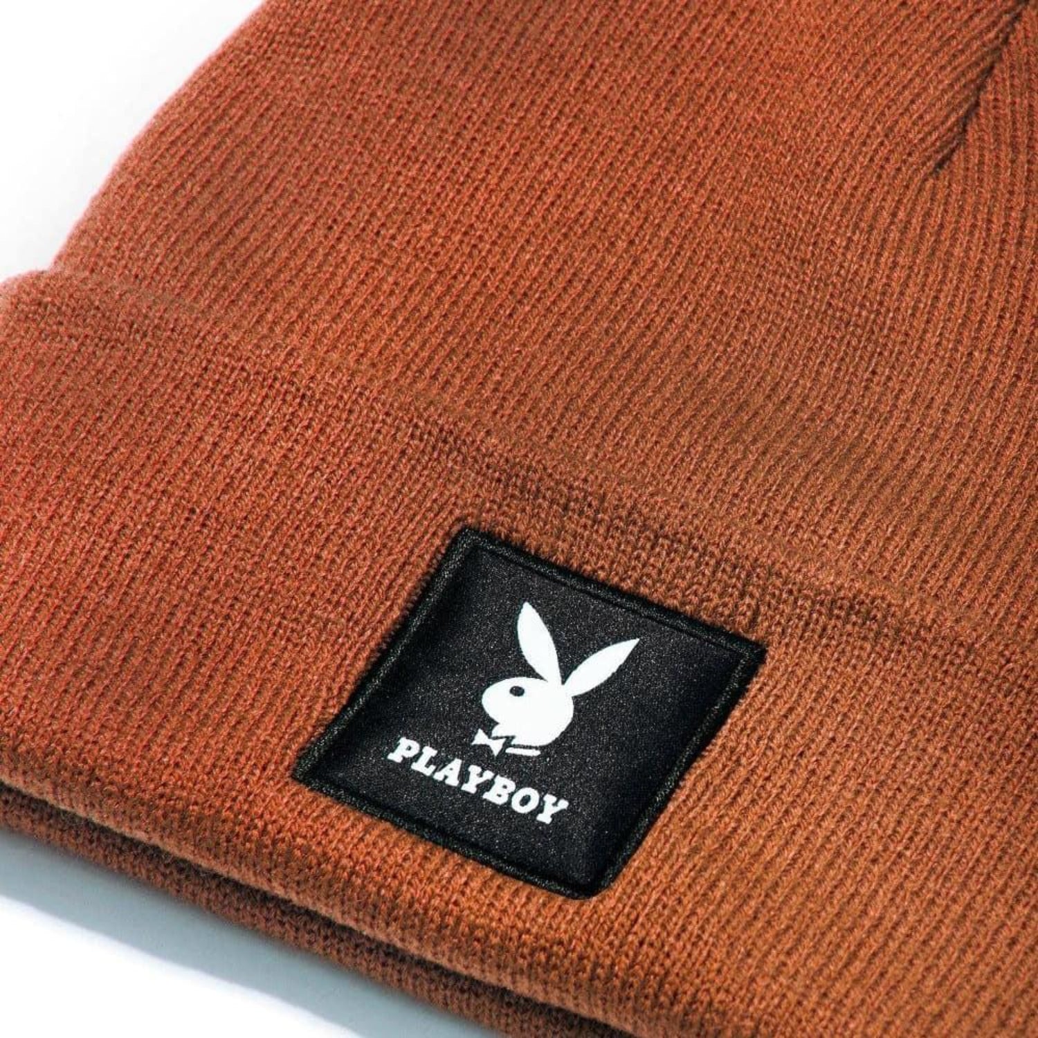Rust knit beanie with black logo patch featuring white bunny graphic and text.