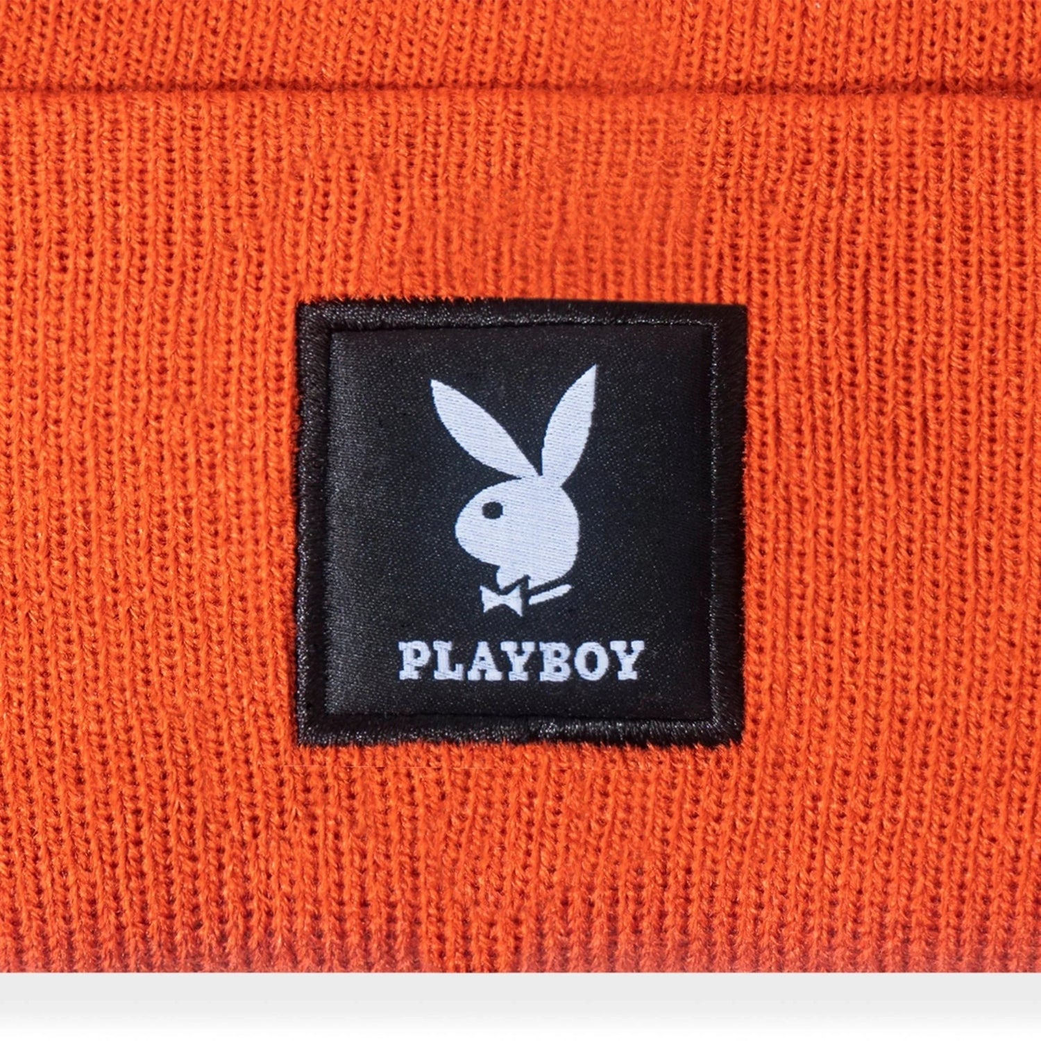 Orange knit beanie with black logo patch featuring white bunny and text