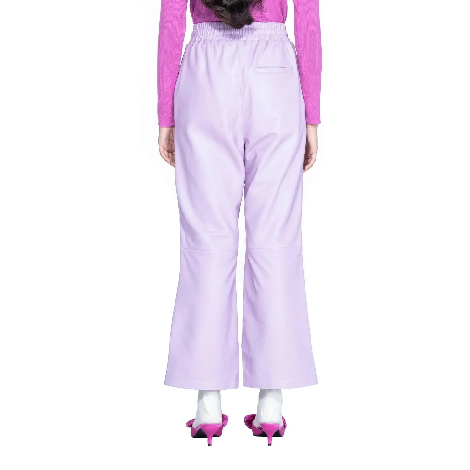 Back view of woman wearing light purple leather flare pants with pink heels and a pink top