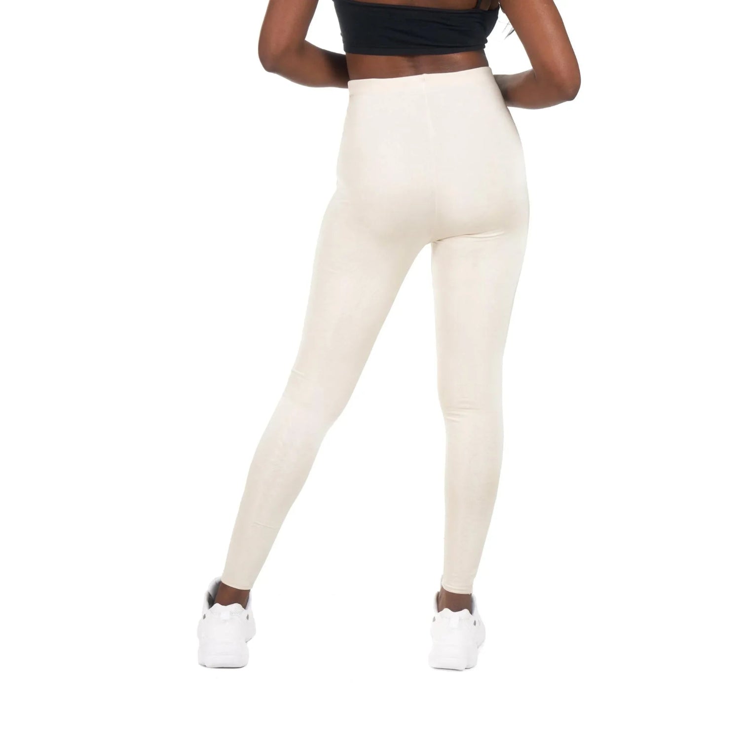 Woman wearing high-waisted cream leggings and white sneakers, back view