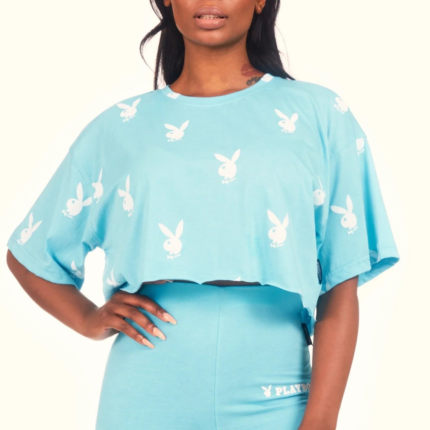 Woman wearing light blue cropped t-shirt with all-over white bunny logo print