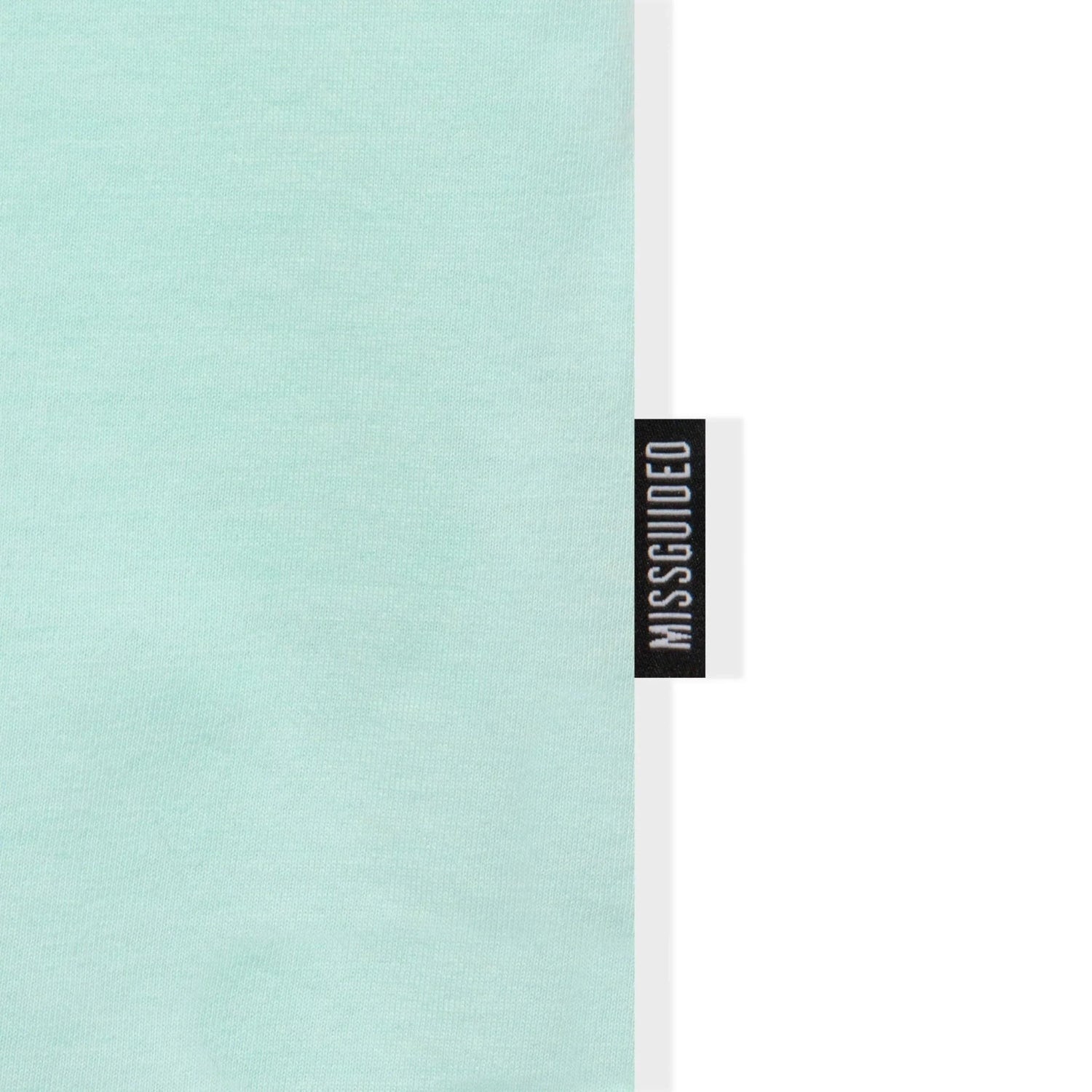 Close-up of light blue oversized T-shirt with black MISS GUIDED label on seam
