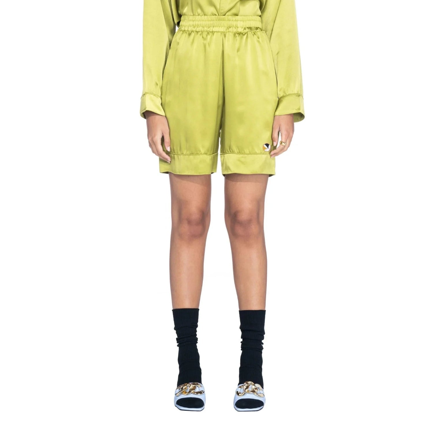 Woman wearing olive green silk shorts with elastic waistband and turned-up hem, front view