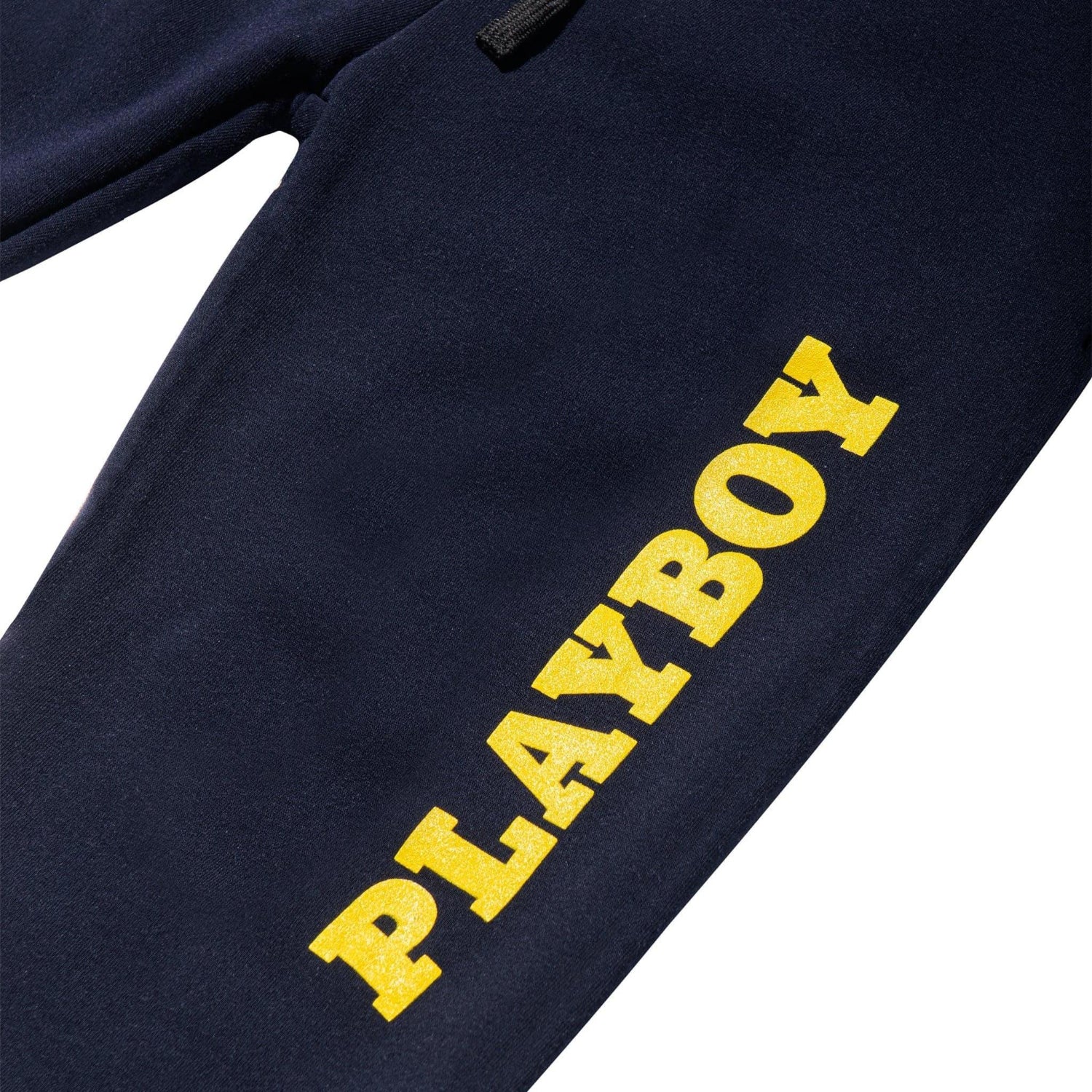 Navy jogger pants with bold yellow PLAYBOY text on the leg, close-up view
