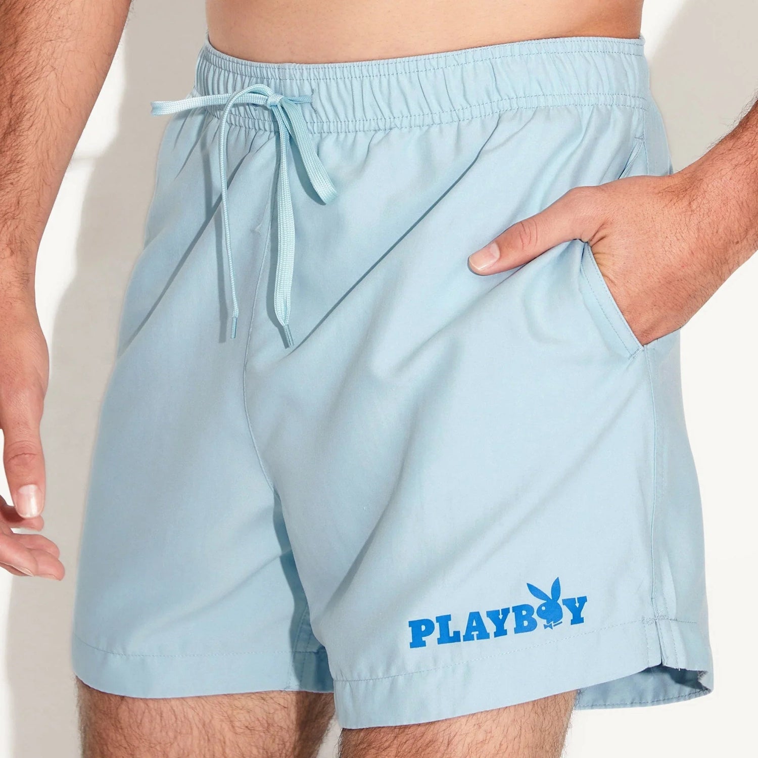 Light blue men's swim trunks with elastic waistband, side pocket, and blue Playboy logo.