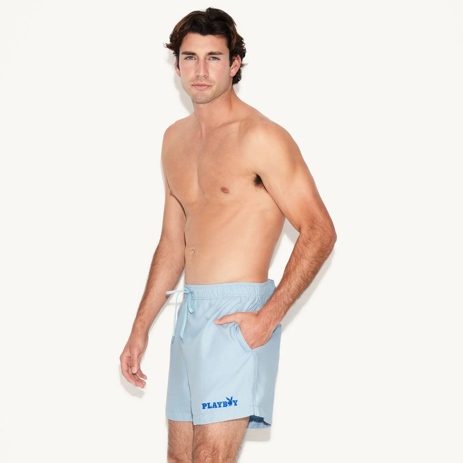 Man modeling light blue men's swim trunks with drawstring waist and blue graphic logo