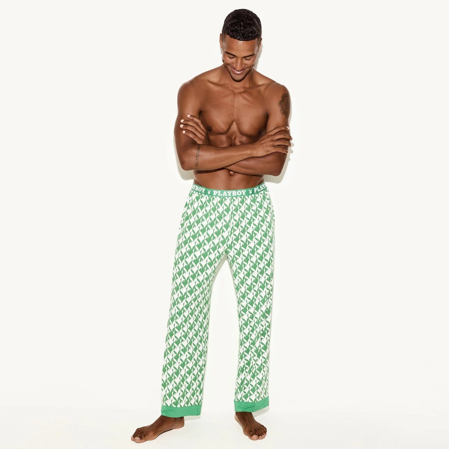 Man wearing green and white patterned pajama pants with visible branded waistband