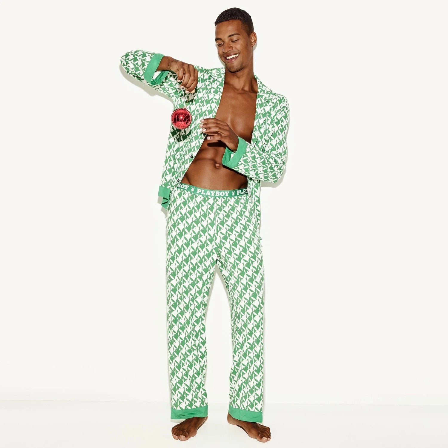 Man wearing green and white patterned men's pajama set, open shirt, playful pose