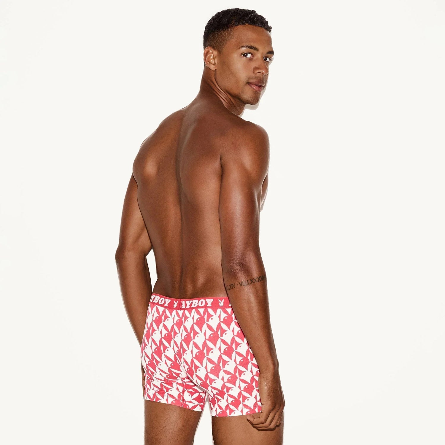 Male model wearing red and white boxer briefs with repeating bunny logo pattern, rear view