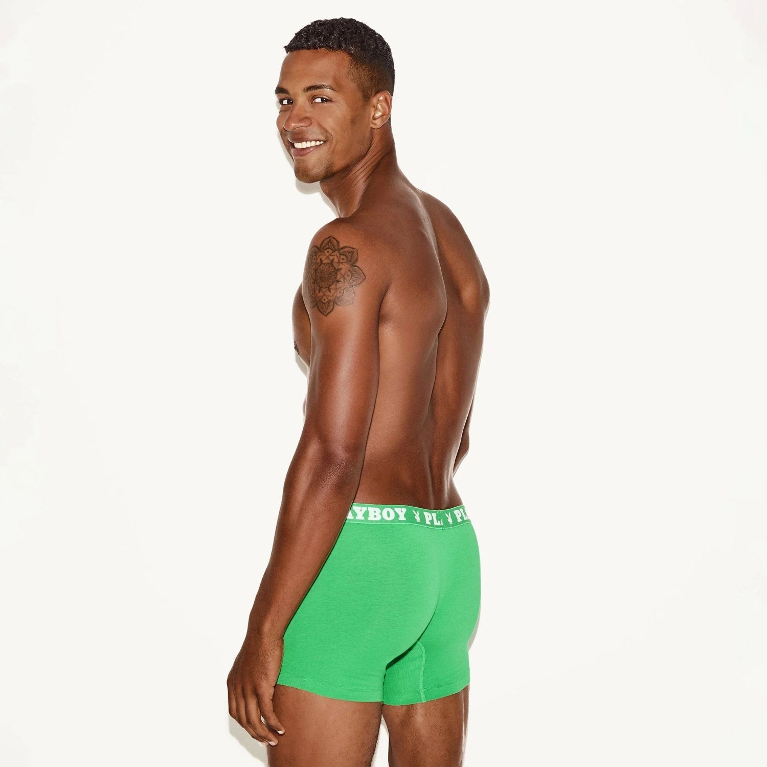 Male model in green boxer briefs with branded waistband, posing against a plain background