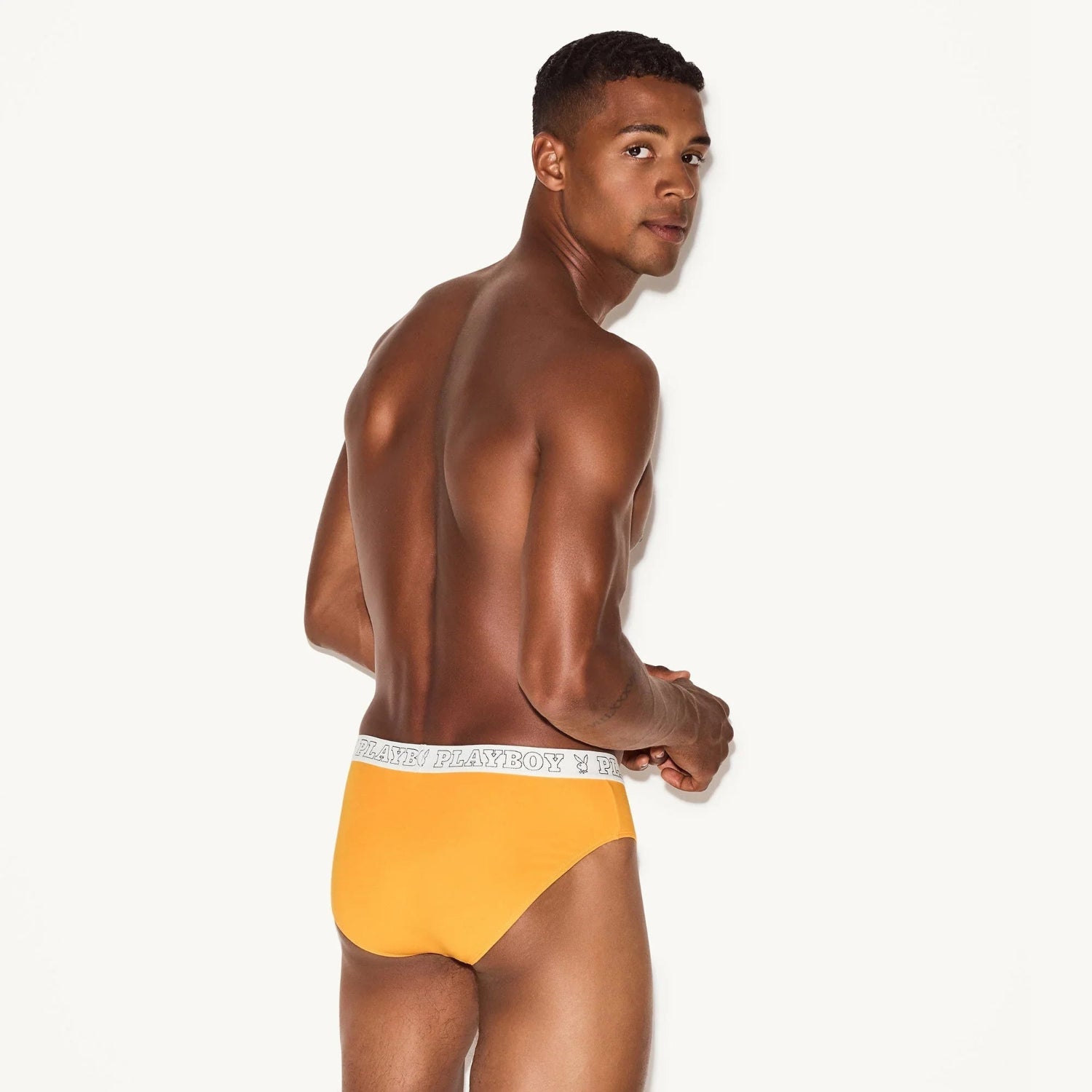 Male model wearing orange modal briefs with branded elastic waistband, back view