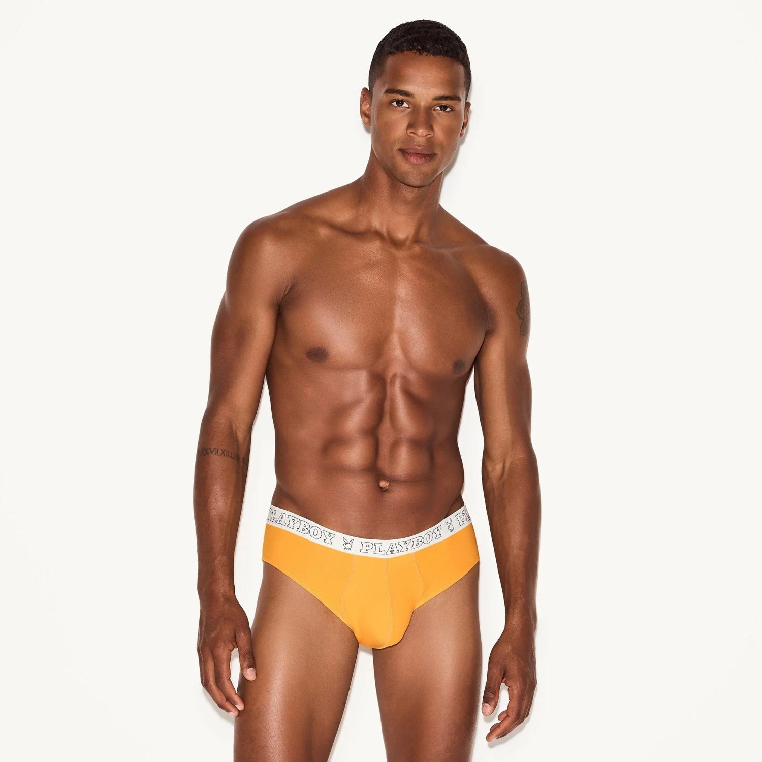 Male model wearing orange men's modal briefs with branded waistband, front view
