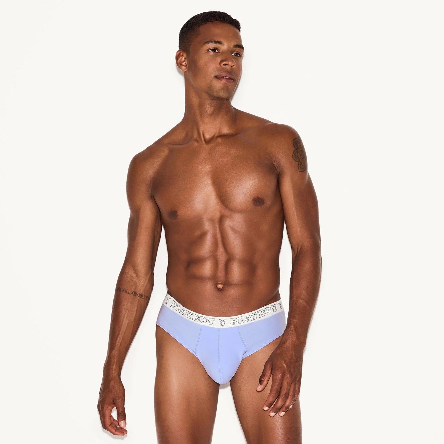 Male model wearing light blue men's modal briefs with branded waistband on white background