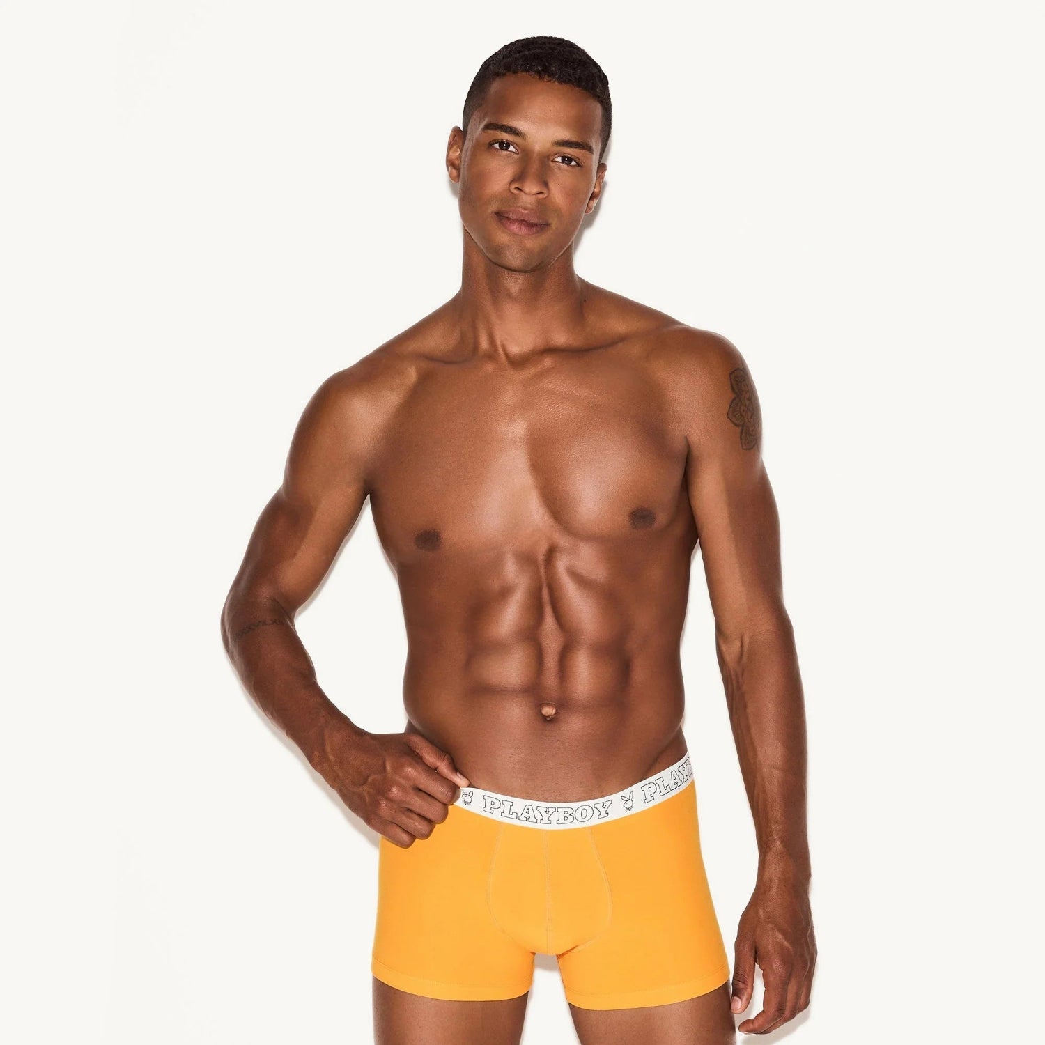 Man modeling orange modal trunk underwear with white waistband and logo on plain background