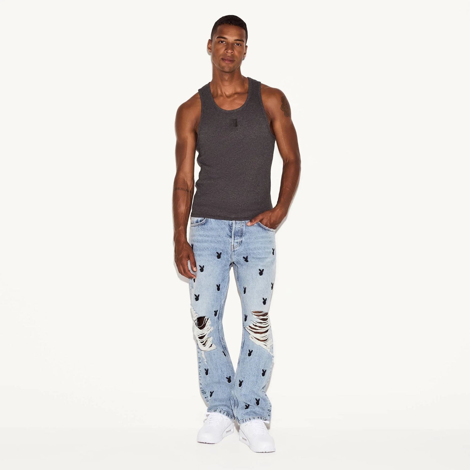 Man wearing a charcoal rib tank top and light blue ripped jeans with bunny head prints