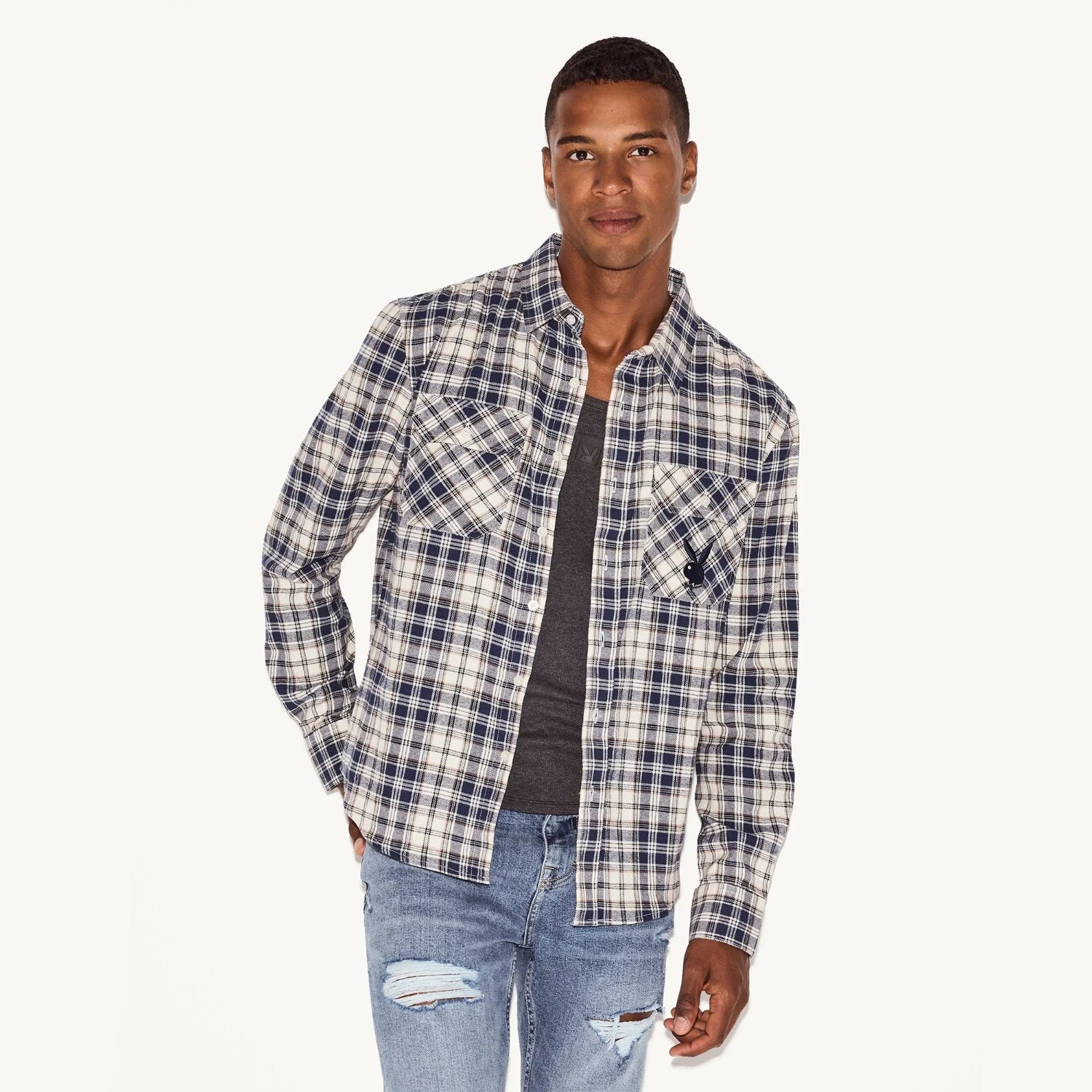 Man wearing blue plaid flannel long sleeve shirt with chest pockets and distressed jeans