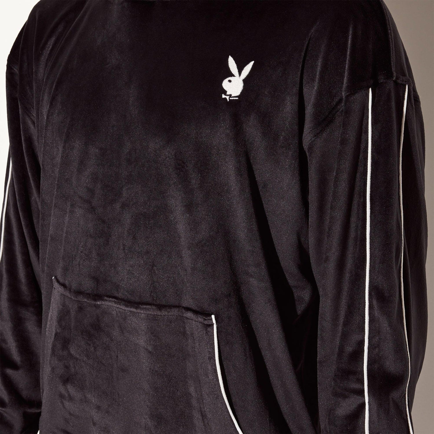 Men's black velour hoodie with white bunny logo, front pocket, and striped sleeves.