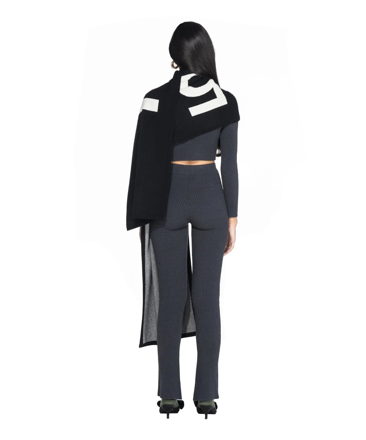 Woman in ribbed gray knit set with long black and white cashmere scarf, back view