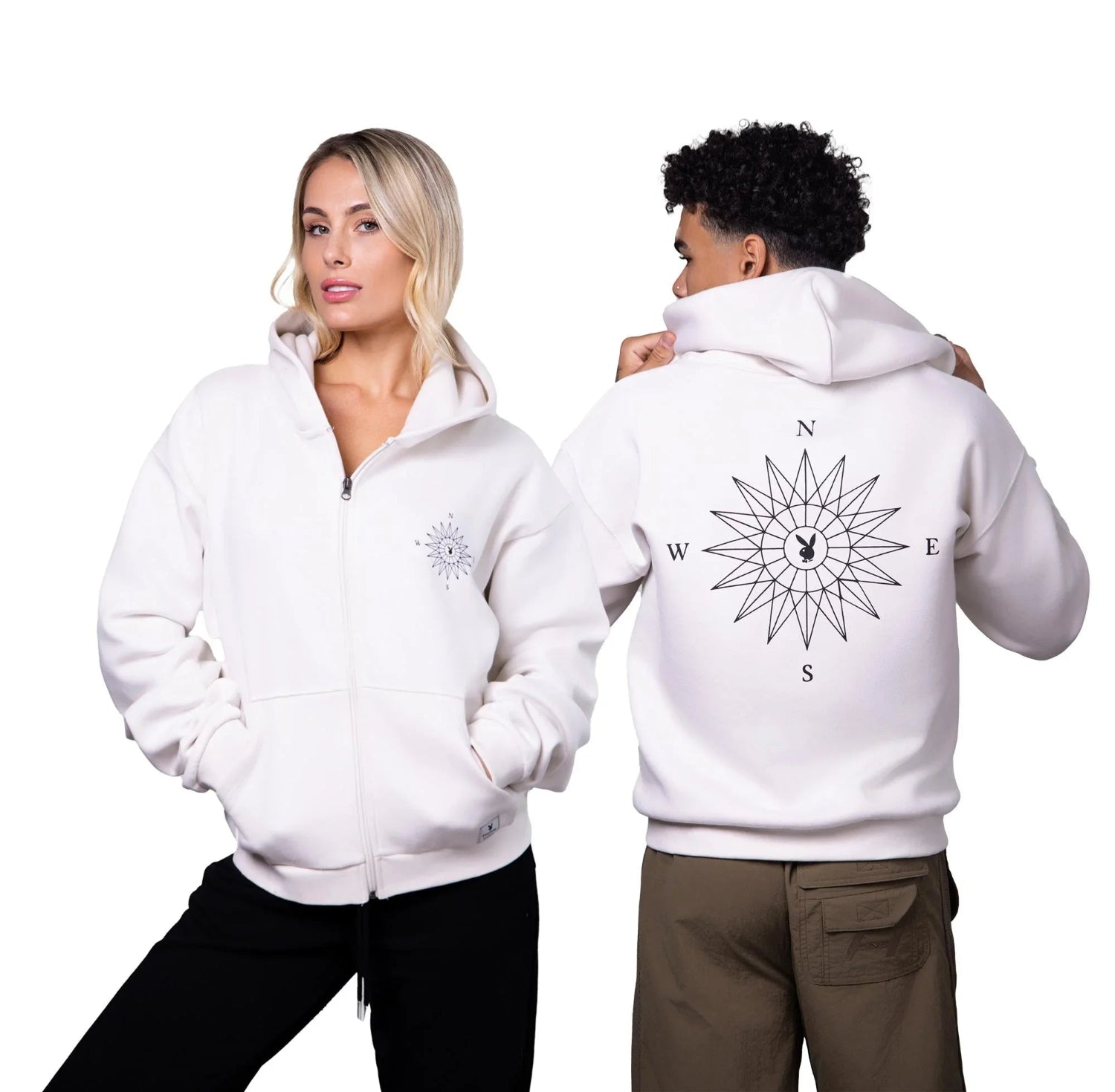 White zip-up hoodie with black compass graphic, modeled front and back by man and woman