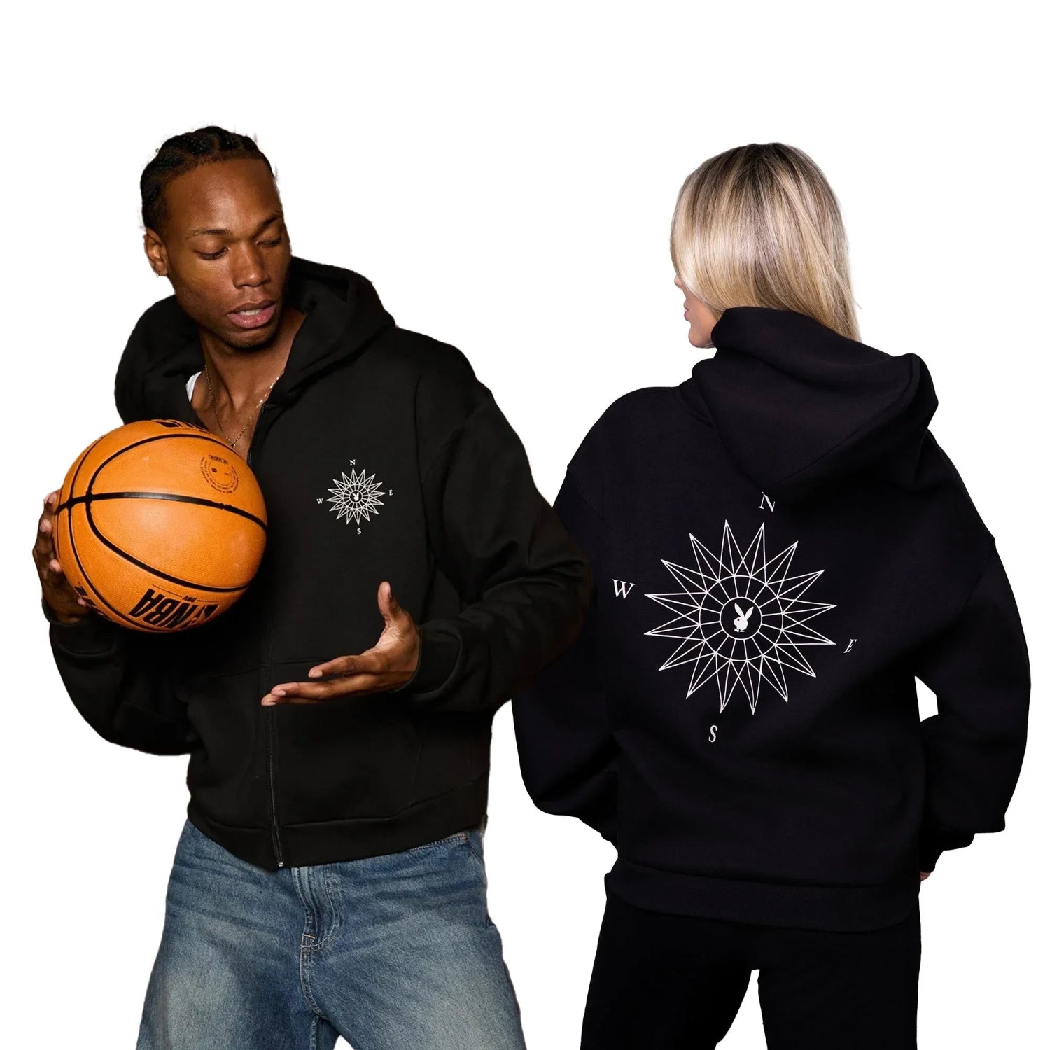 Black zip hoodie with white compass graphic, modeled by man with basketball and woman showing back design