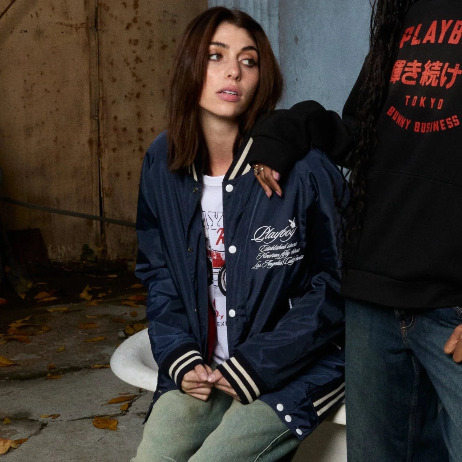 Woman wearing navy blue unisex varsity jacket with embroidered script and casual streetwear style