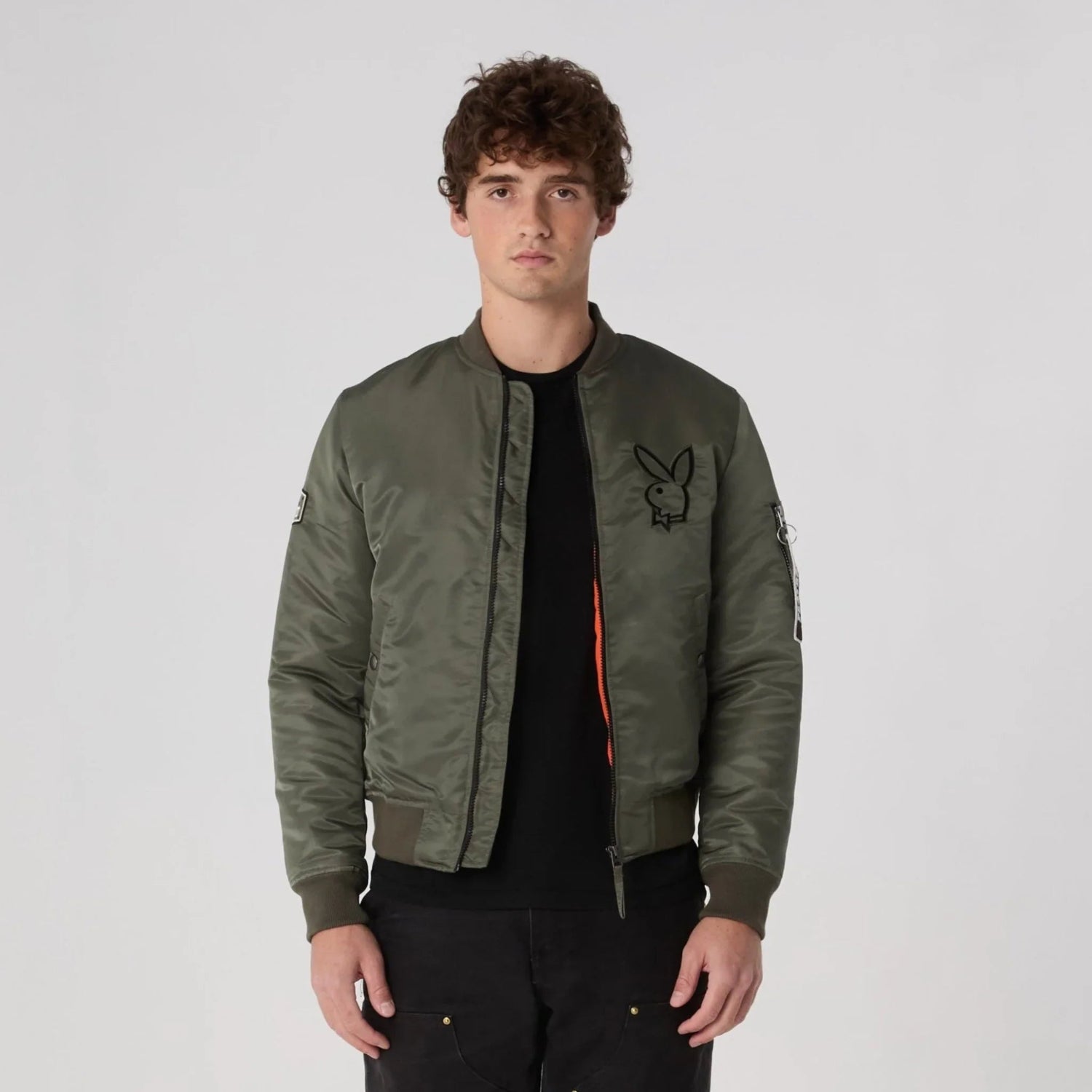Man wearing khaki green bomber jacket with bunny logo and zipper sleeve detail