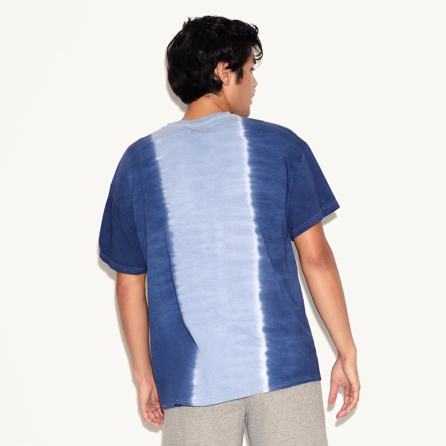 Back view of a man wearing a blue and white vertical tie-dye short sleeve t-shirt