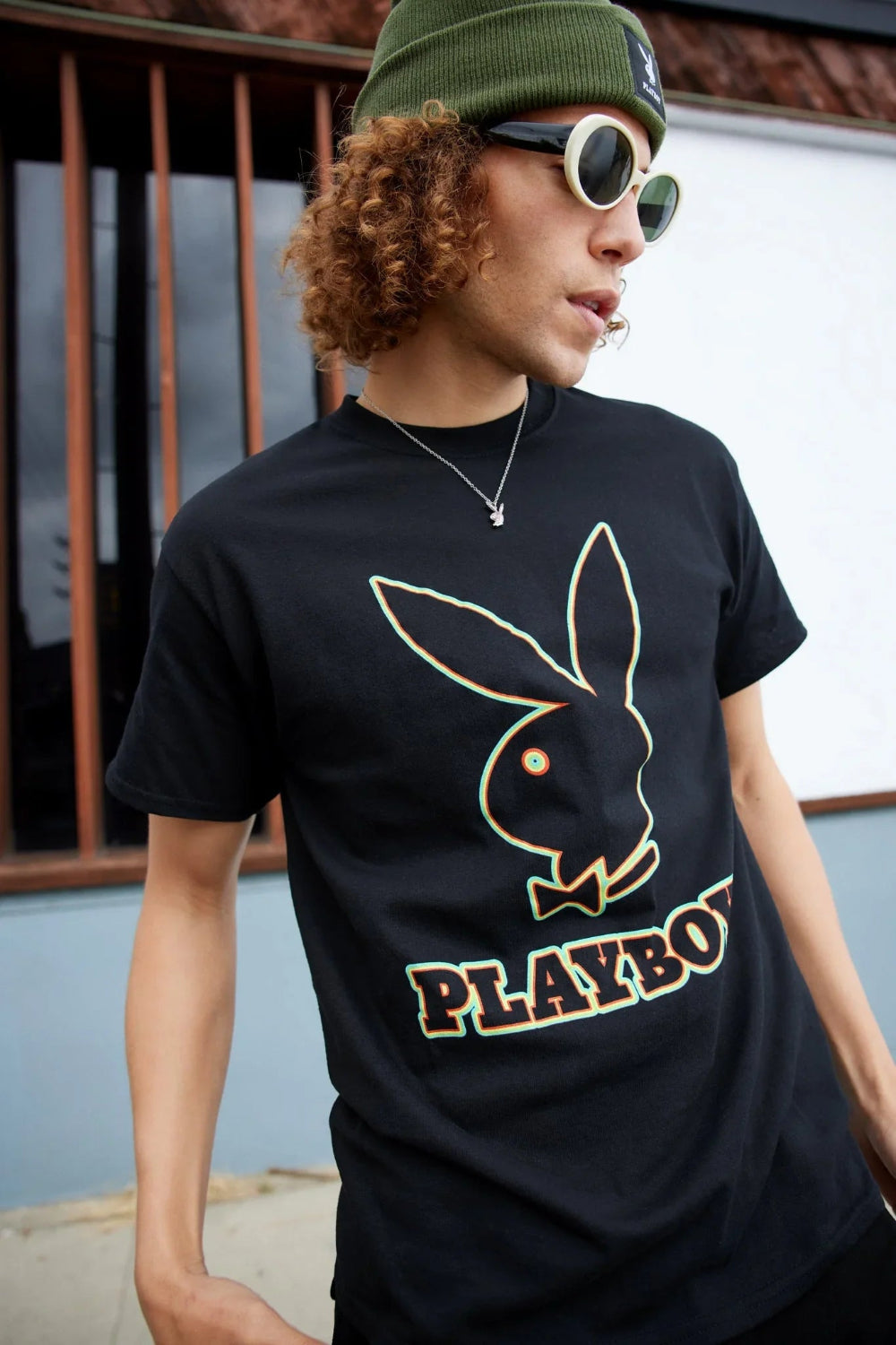 Man wearing black graphic t-shirt with large outlined bunny logo and PLAYBOY text outdoors
