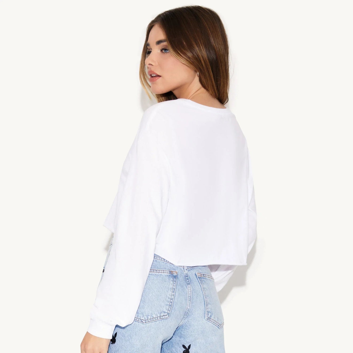 Woman wearing white cropped long sleeve tee and light blue jeans with black bunny logo