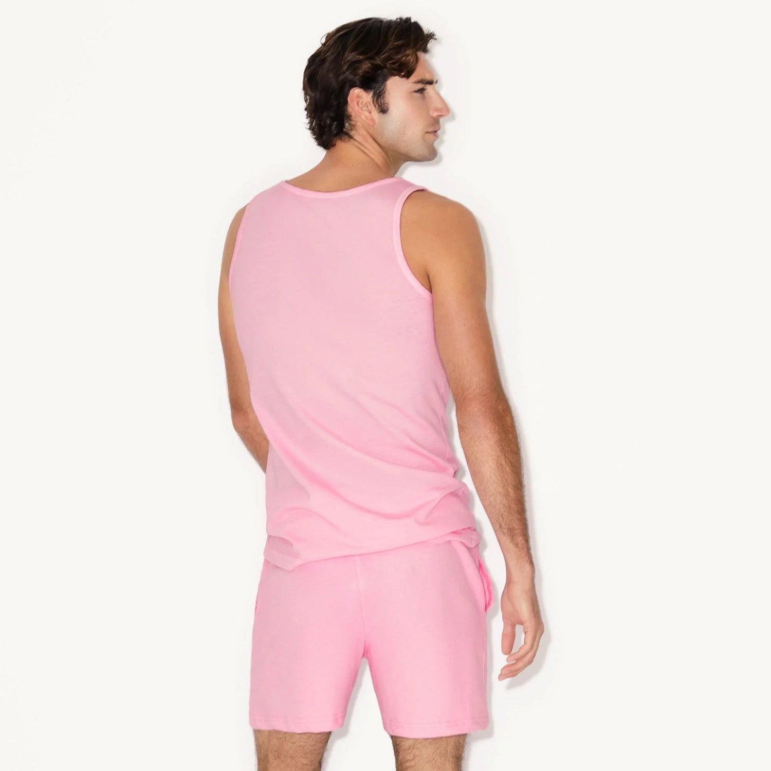 Man wearing pink tank top and pink sweatshorts, viewed from the back
