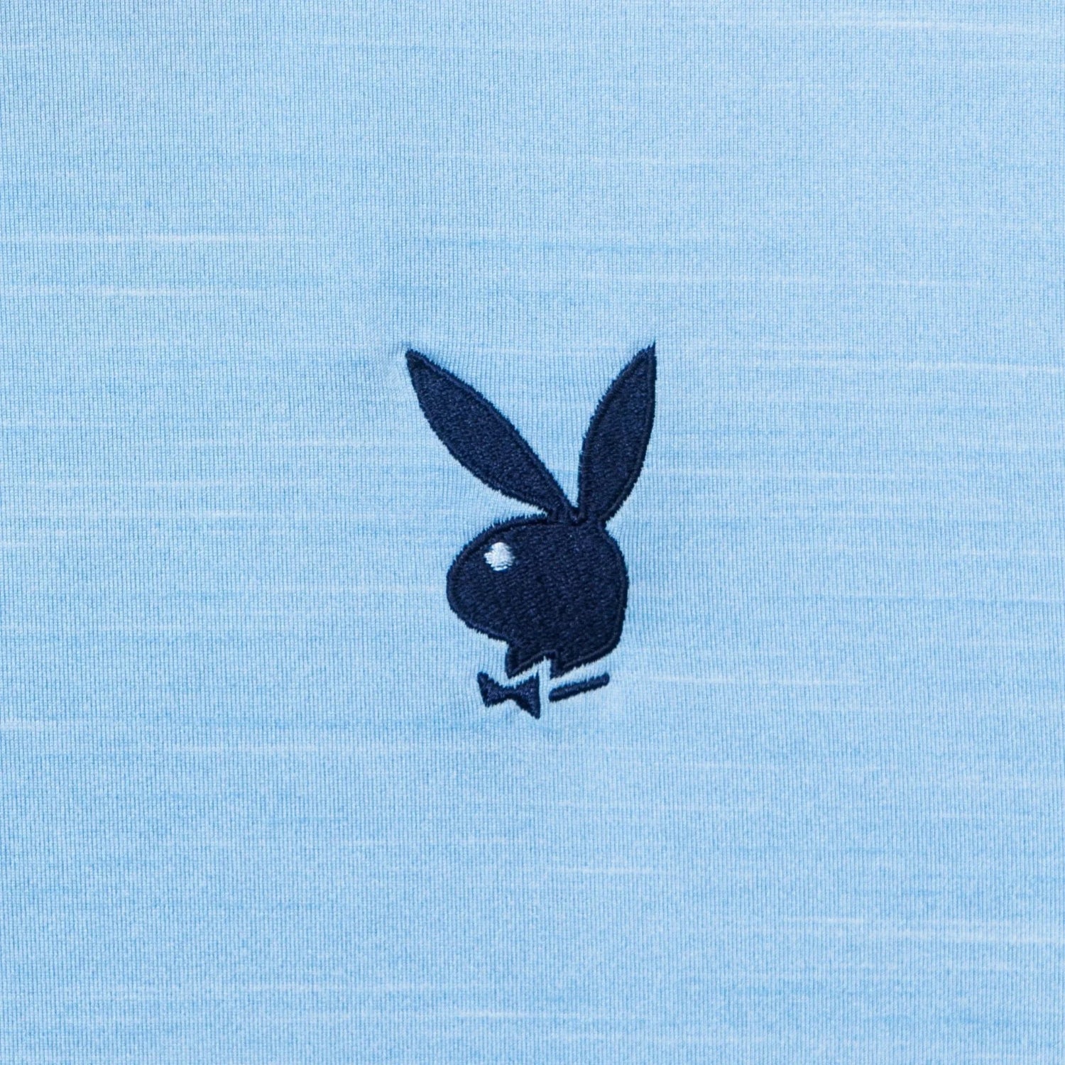 Close-up of embroidered bunny logo on light blue performance polo shirt fabric