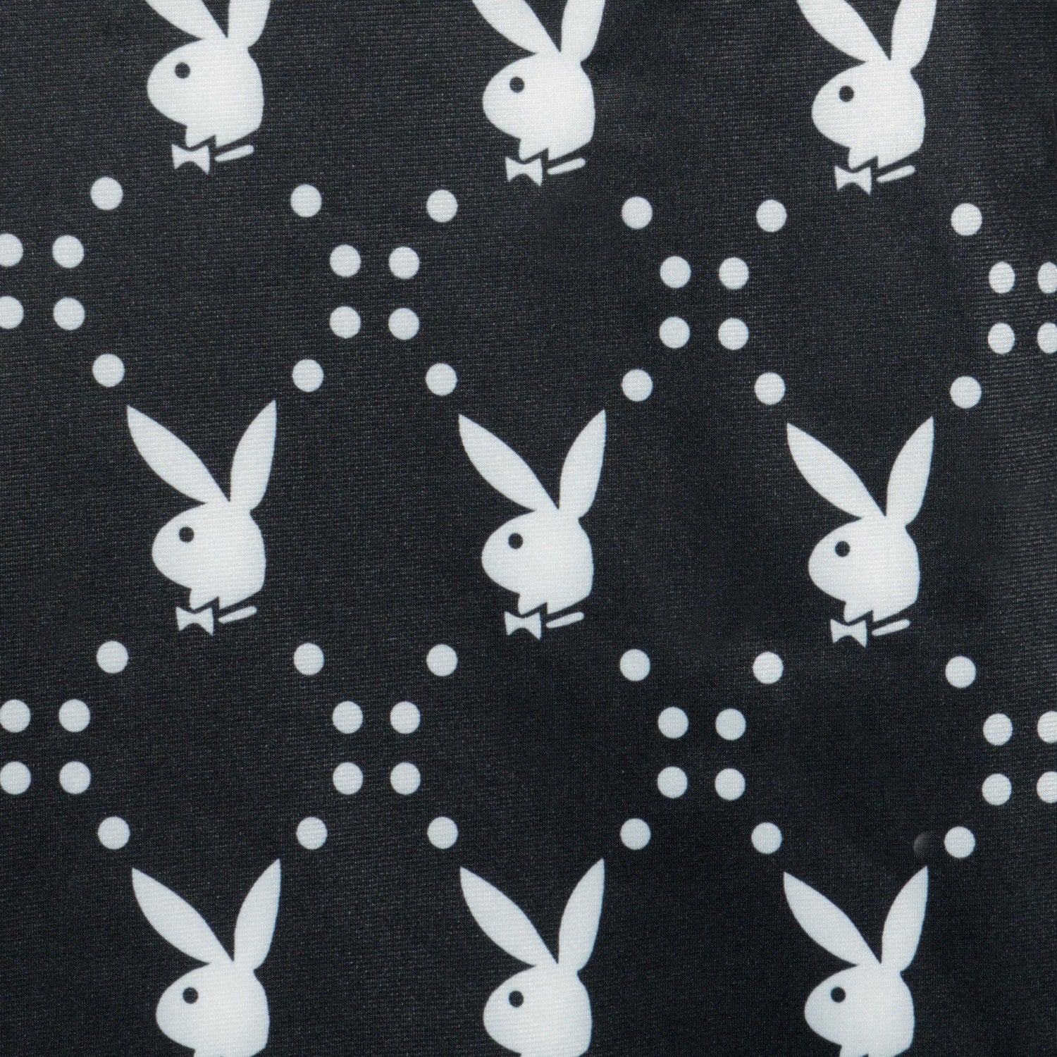 Black fabric with repeating white rabbit head and bowtie pattern, close-up textile design