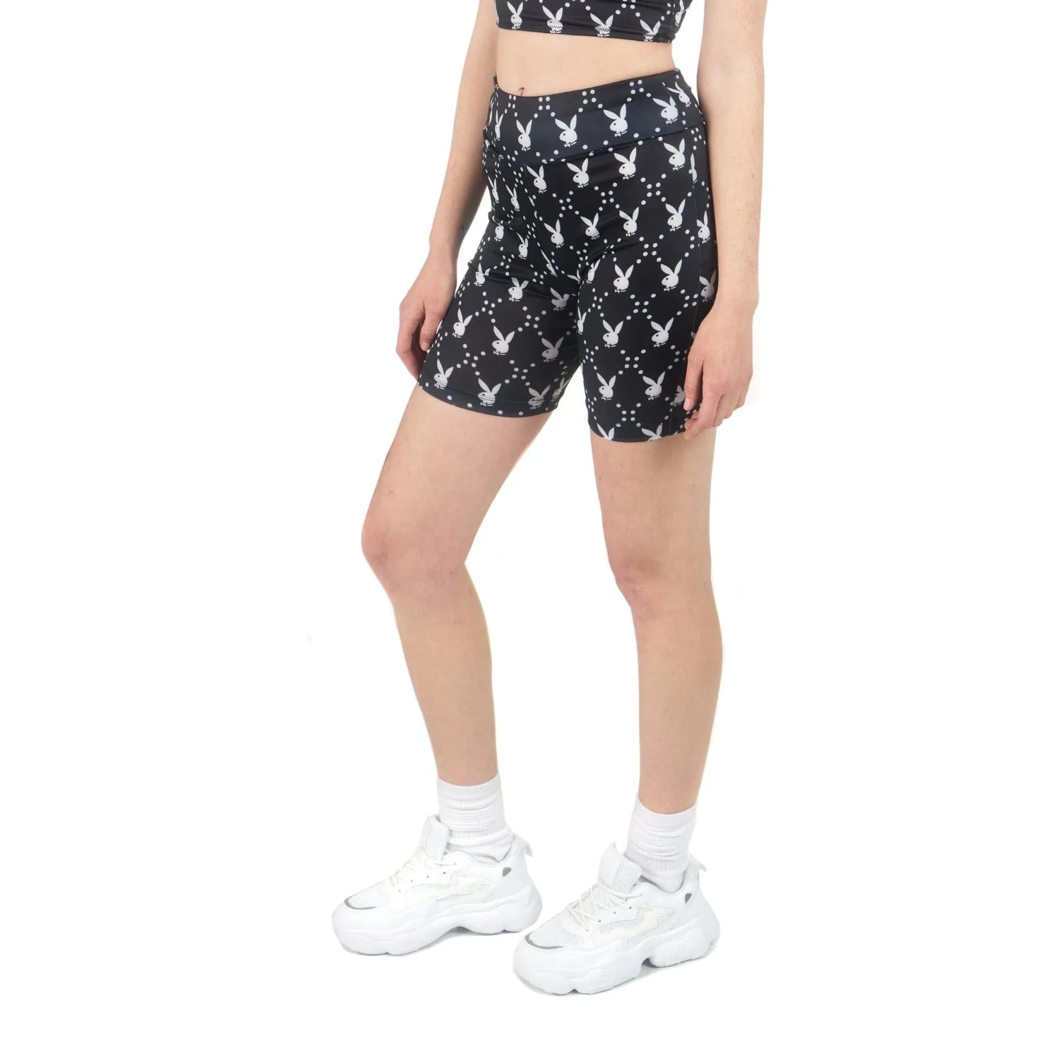 Woman wearing black biker shorts with white rabbit head print, white sneakers and socks