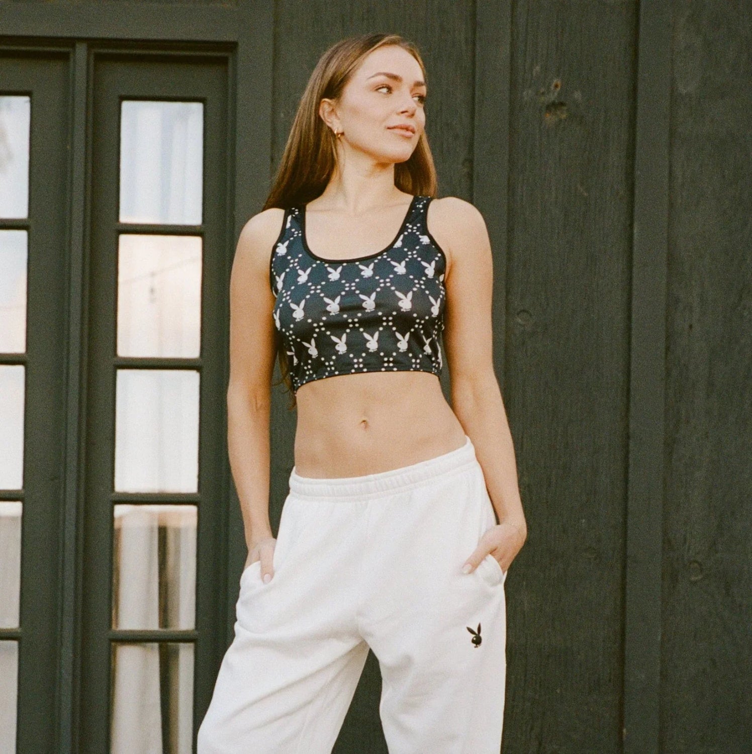 Woman in cropped black tank top with white bunny print and white sweatpants outdoors