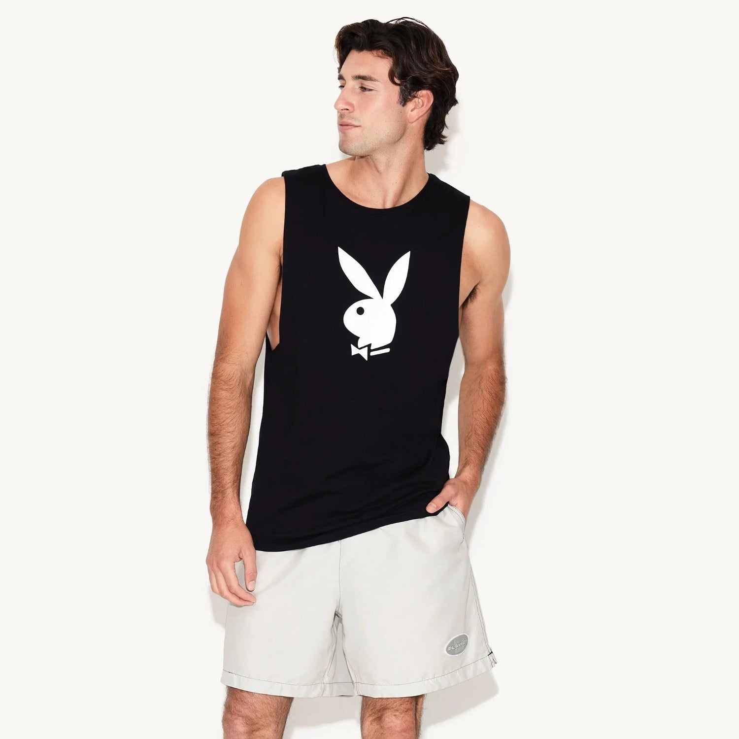 Man wearing black muscle tank with white rabbit head graphic and light shorts