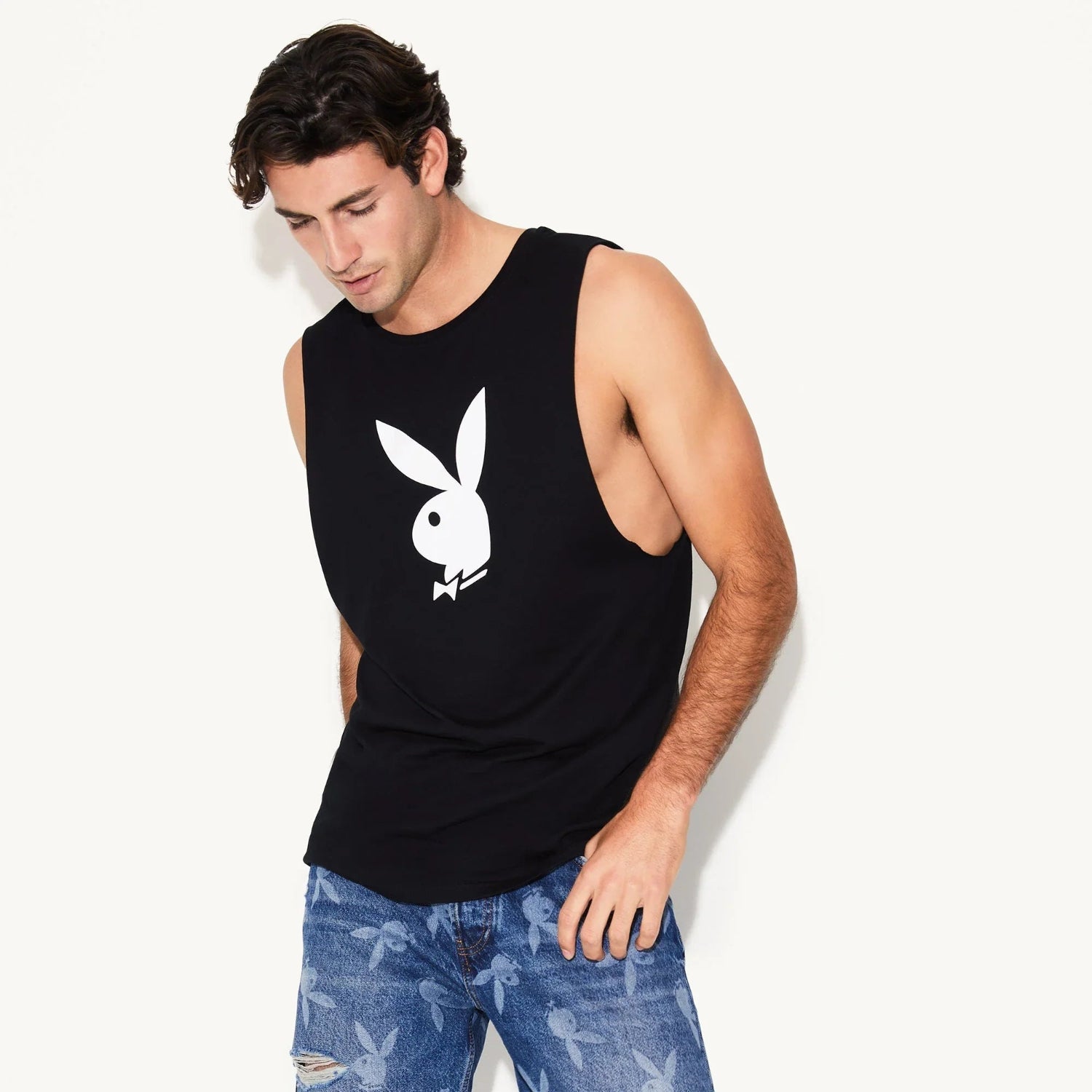 Man wearing black muscle tank top with white rabbit head graphic and blue jeans with rabbit print