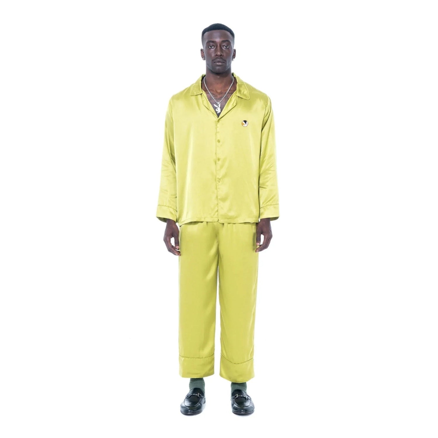 Man wearing yellow silk button-down collared top and matching pants on white background