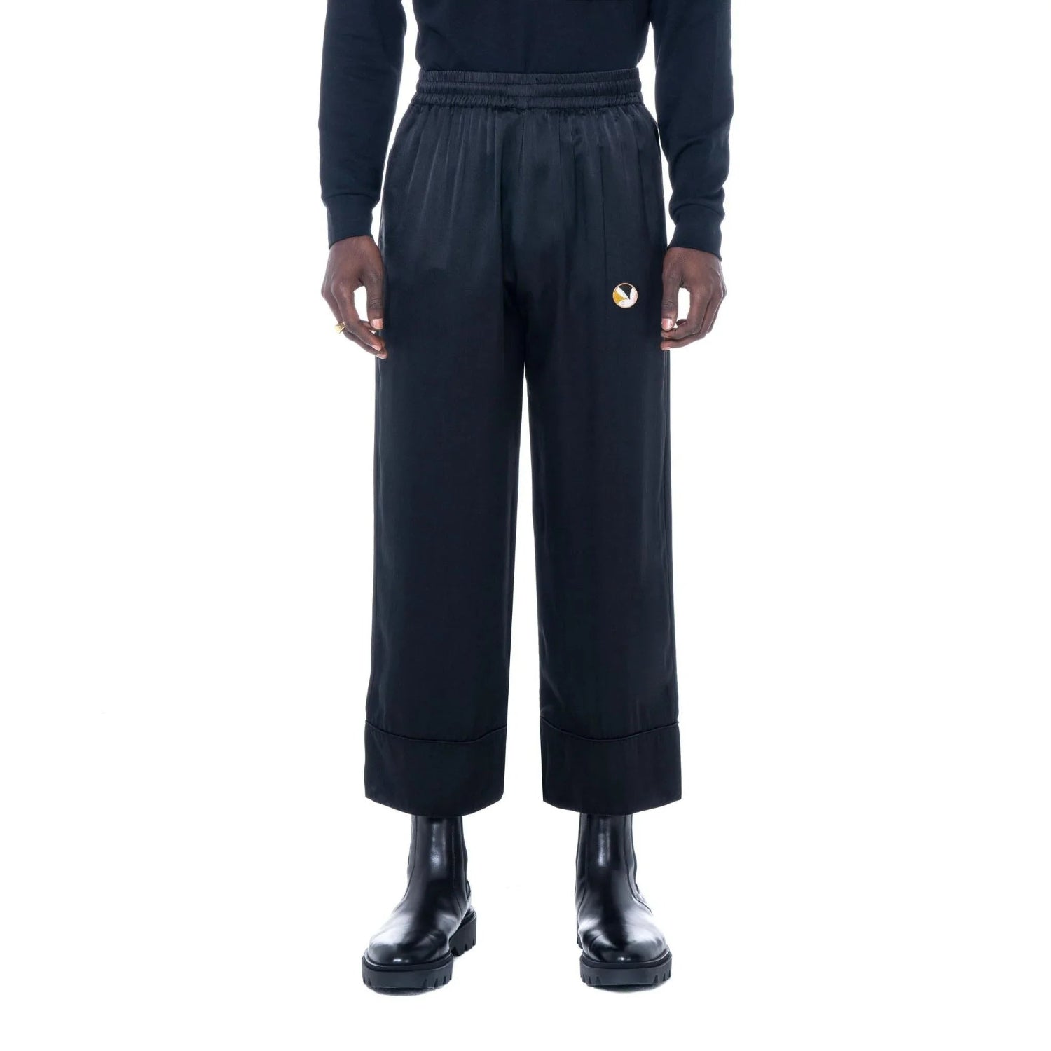 Black silk lounge pants with wide legs and embroidered logo, modeled with black boots