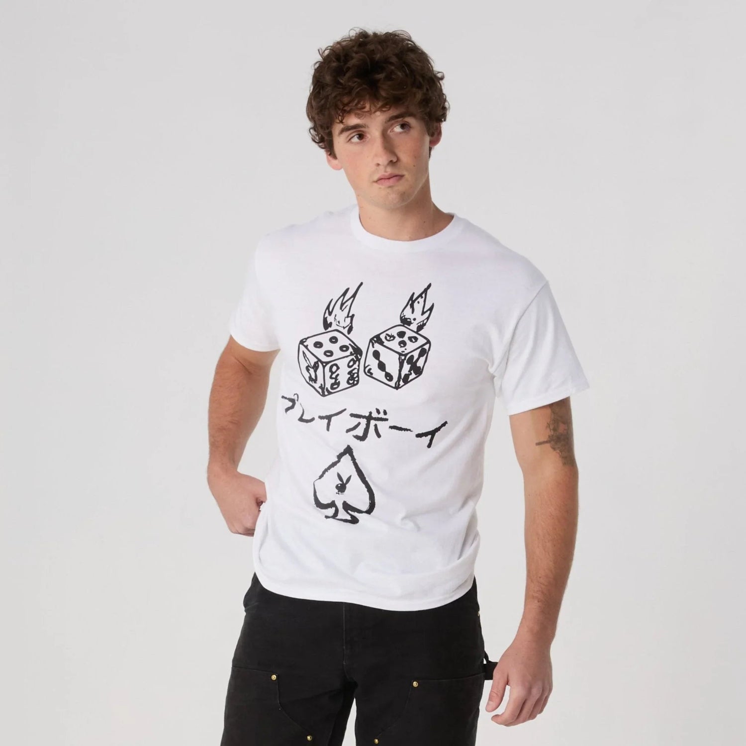 Man in white graphic tee with flaming dice, spade, and Japanese text, casual fashion