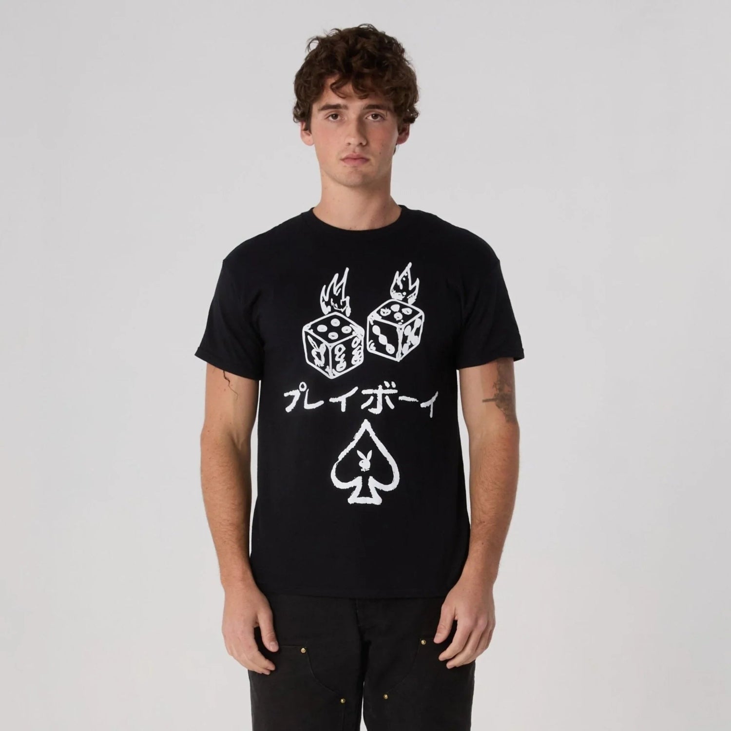 Man wearing black graphic tee with flaming dice, Japanese text, and spade symbol