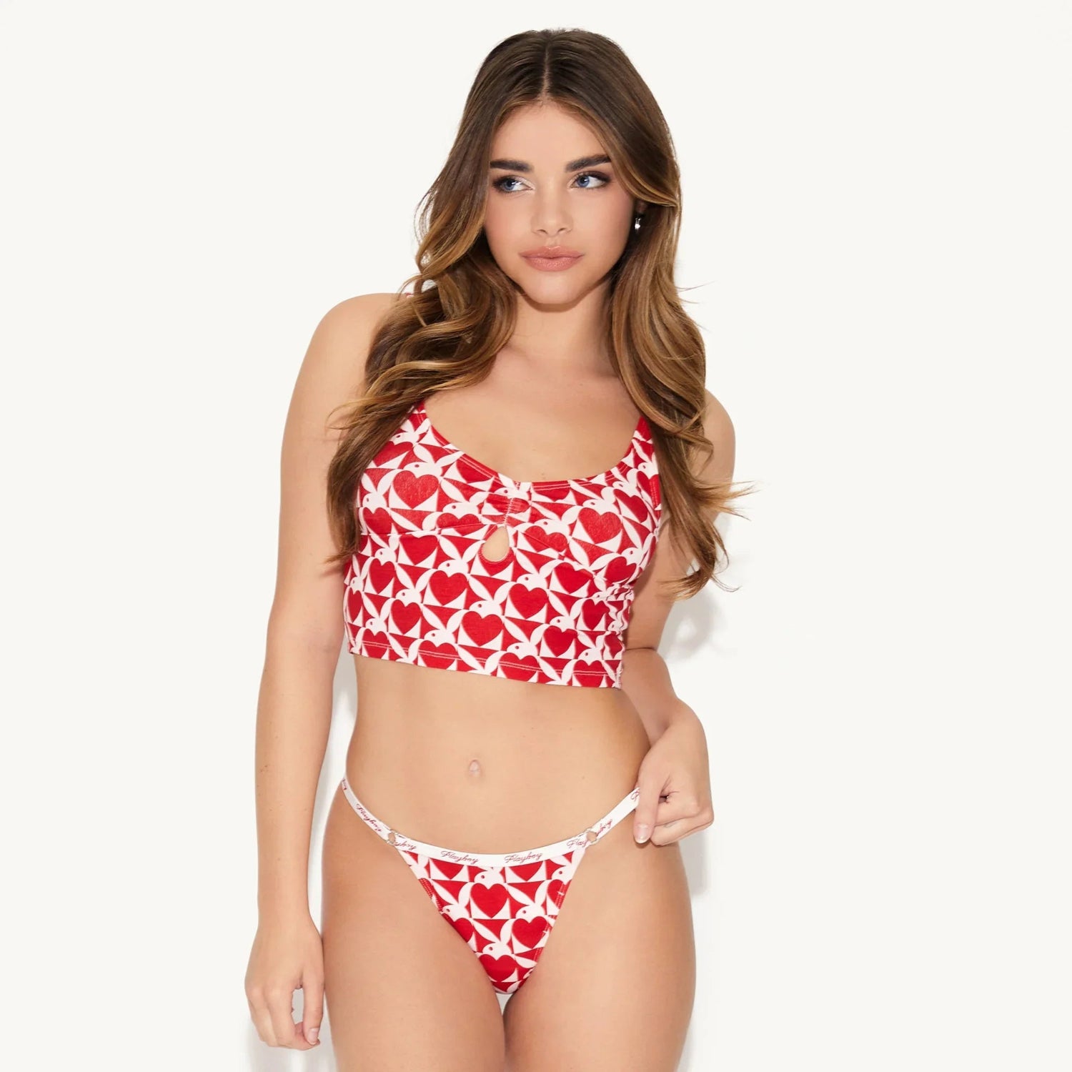 Woman modeling red and white heart print cami and thong set against white background