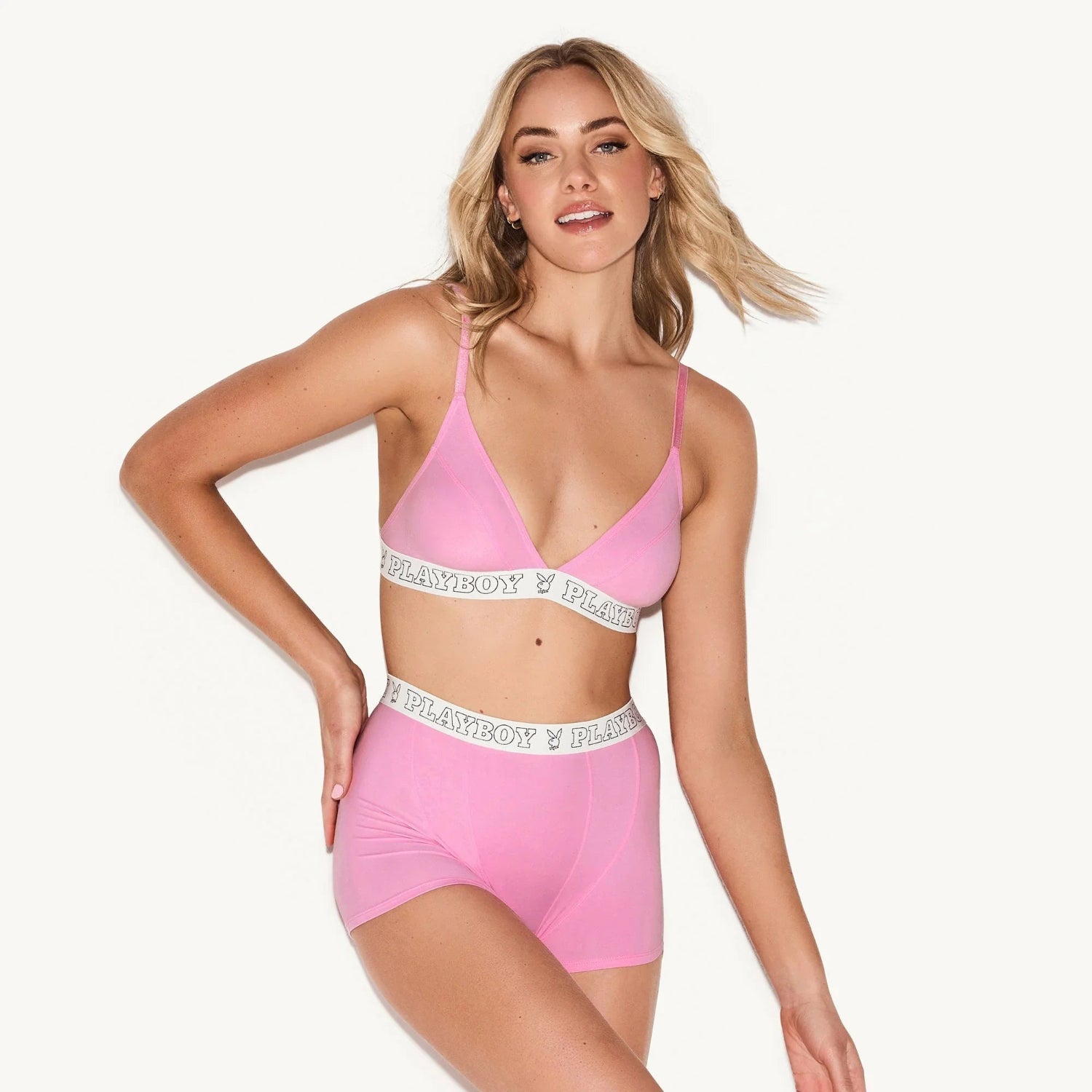 Woman wearing pink modal boxer briefs and bralette with logo waistband on light background