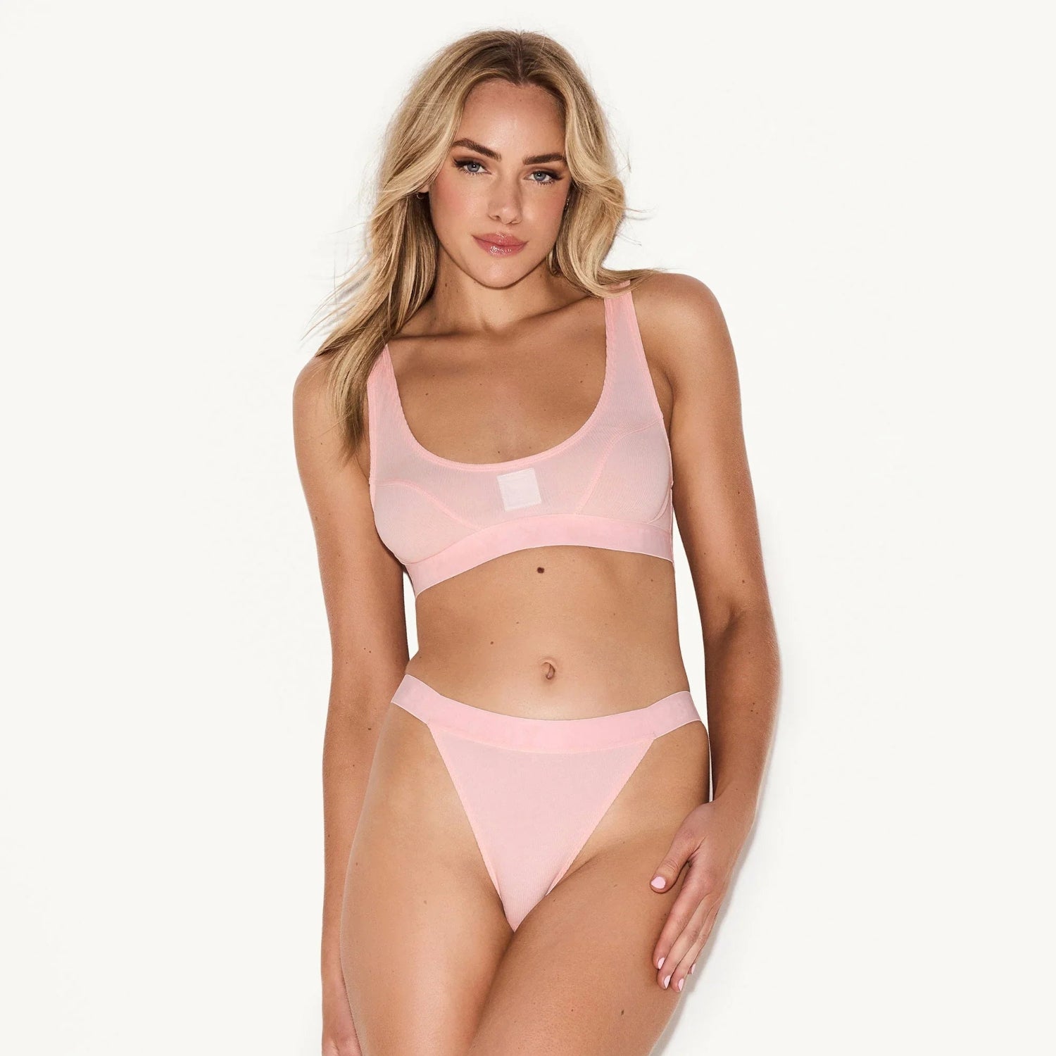 Woman wearing light pink ribbed scoop neck bra and matching high-cut underwear