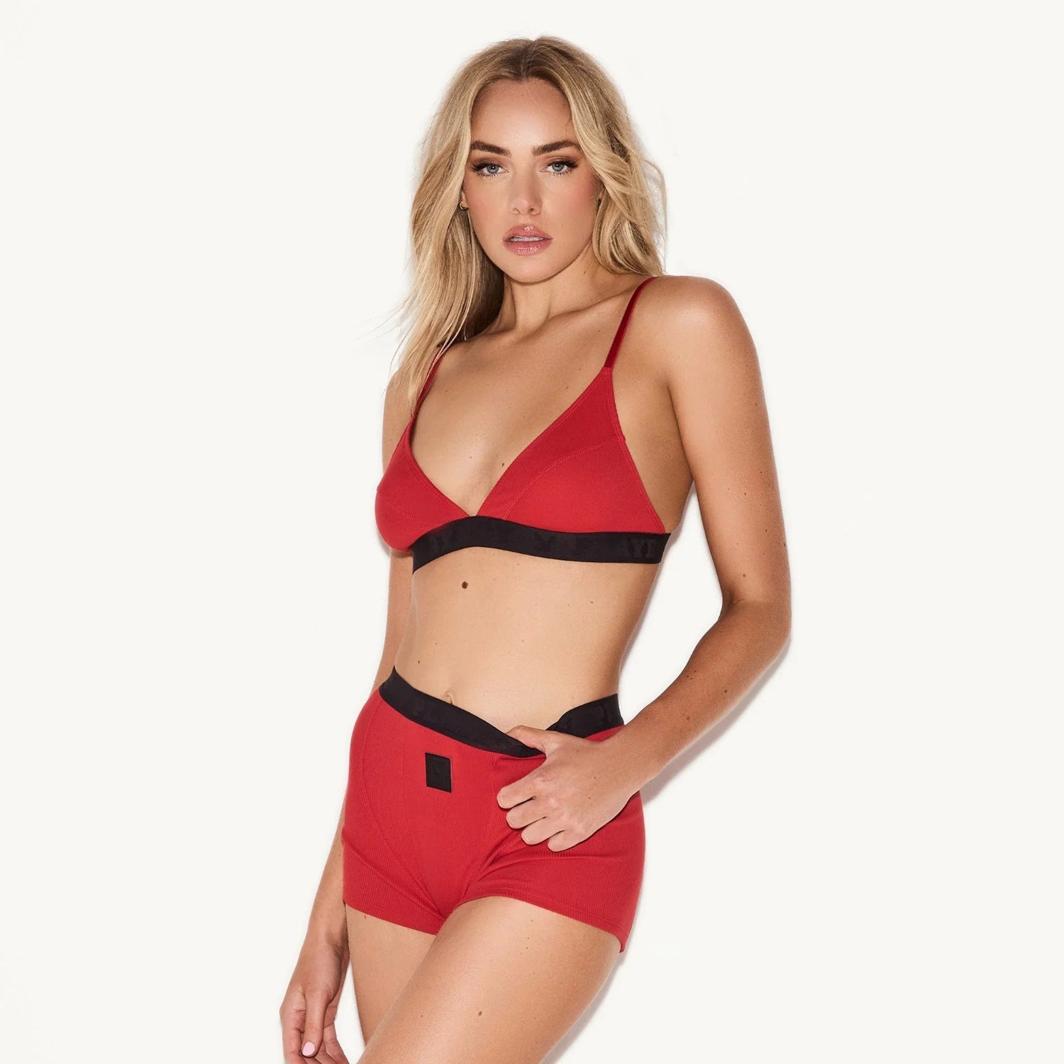 Woman modeling red ribbed triangle bralette and matching high-waisted shorts lingerie set
